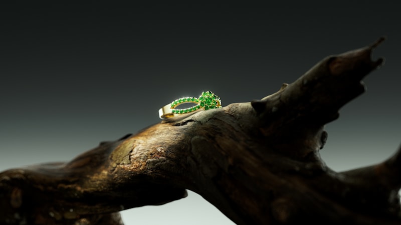 Goldring mit grünen Steinen auf Holzoberfläche