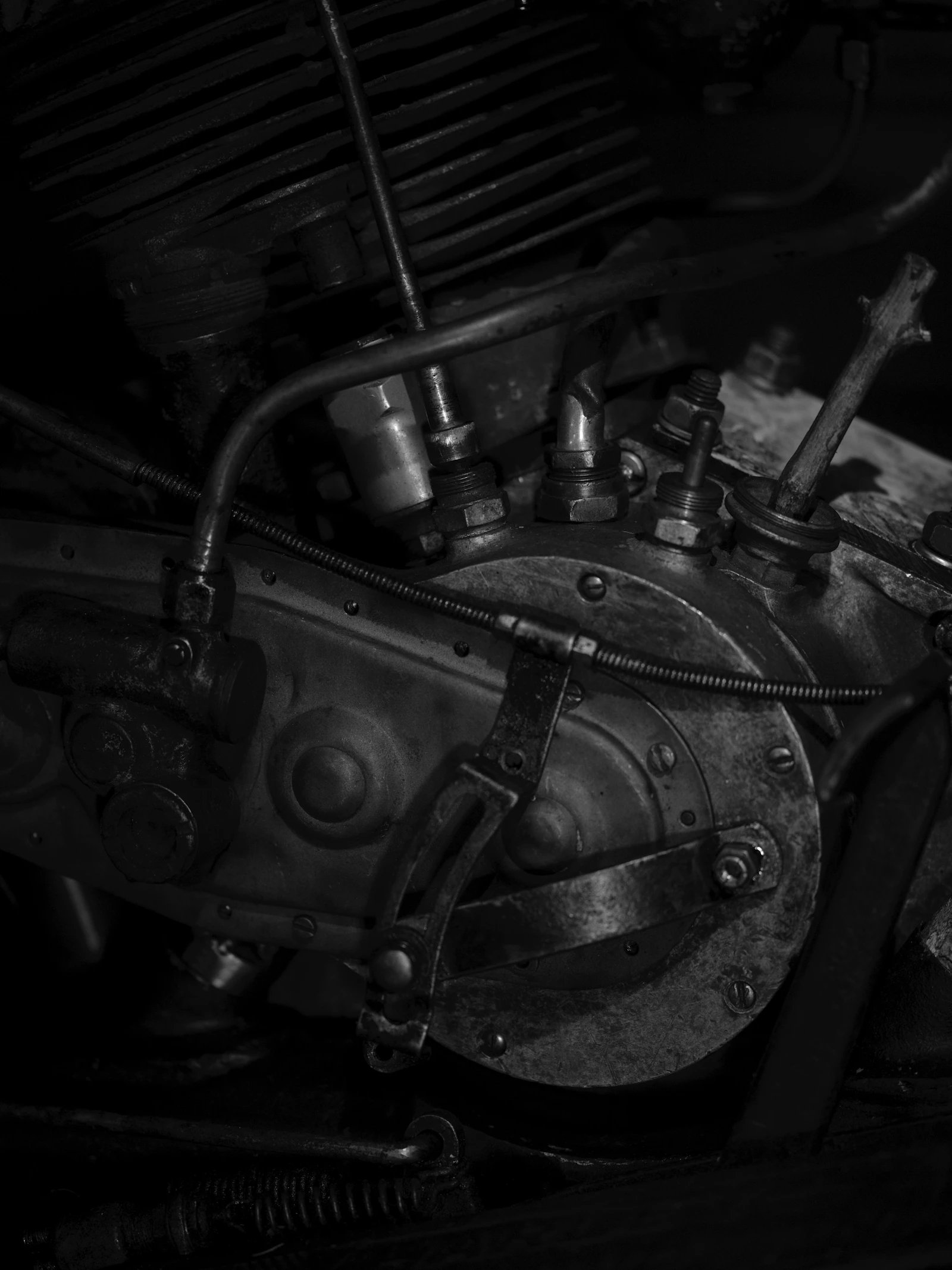Black and white close-up of a vintage motorcycle engine showing pushrod tubes and cooling fins