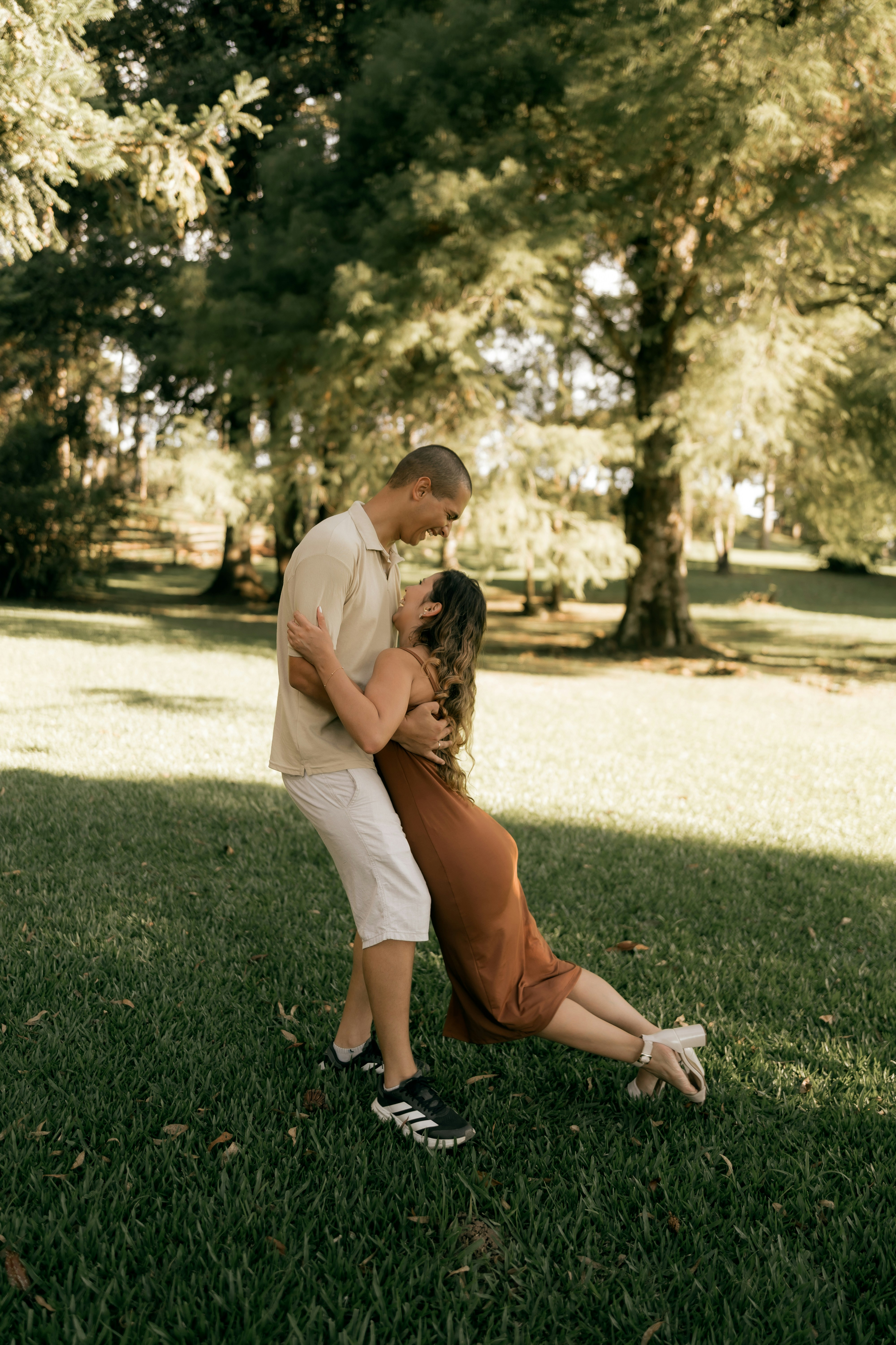 Couple embracing in a grassy park with trees