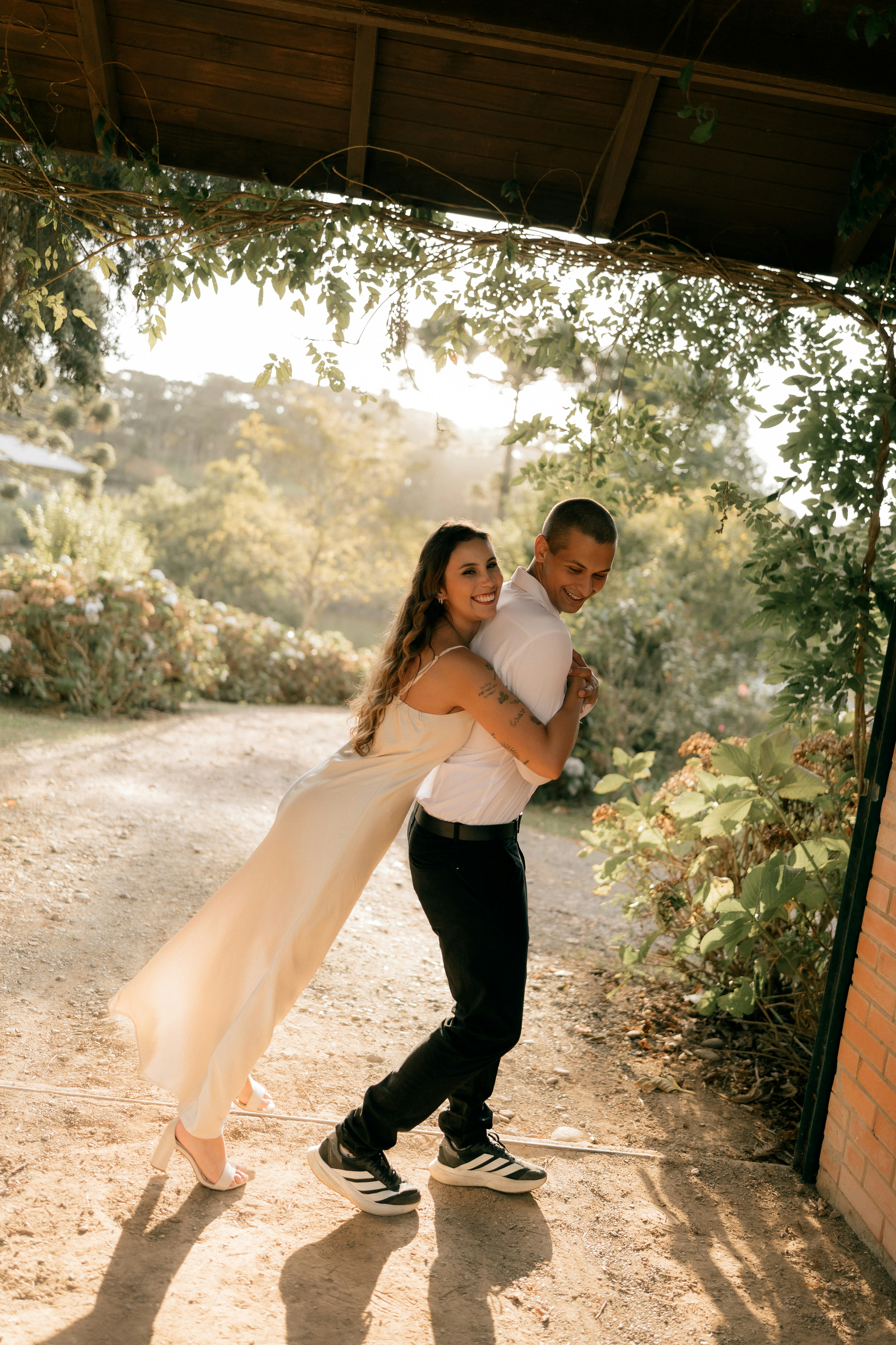 A couple embraces playfully outdoors in sunlight.