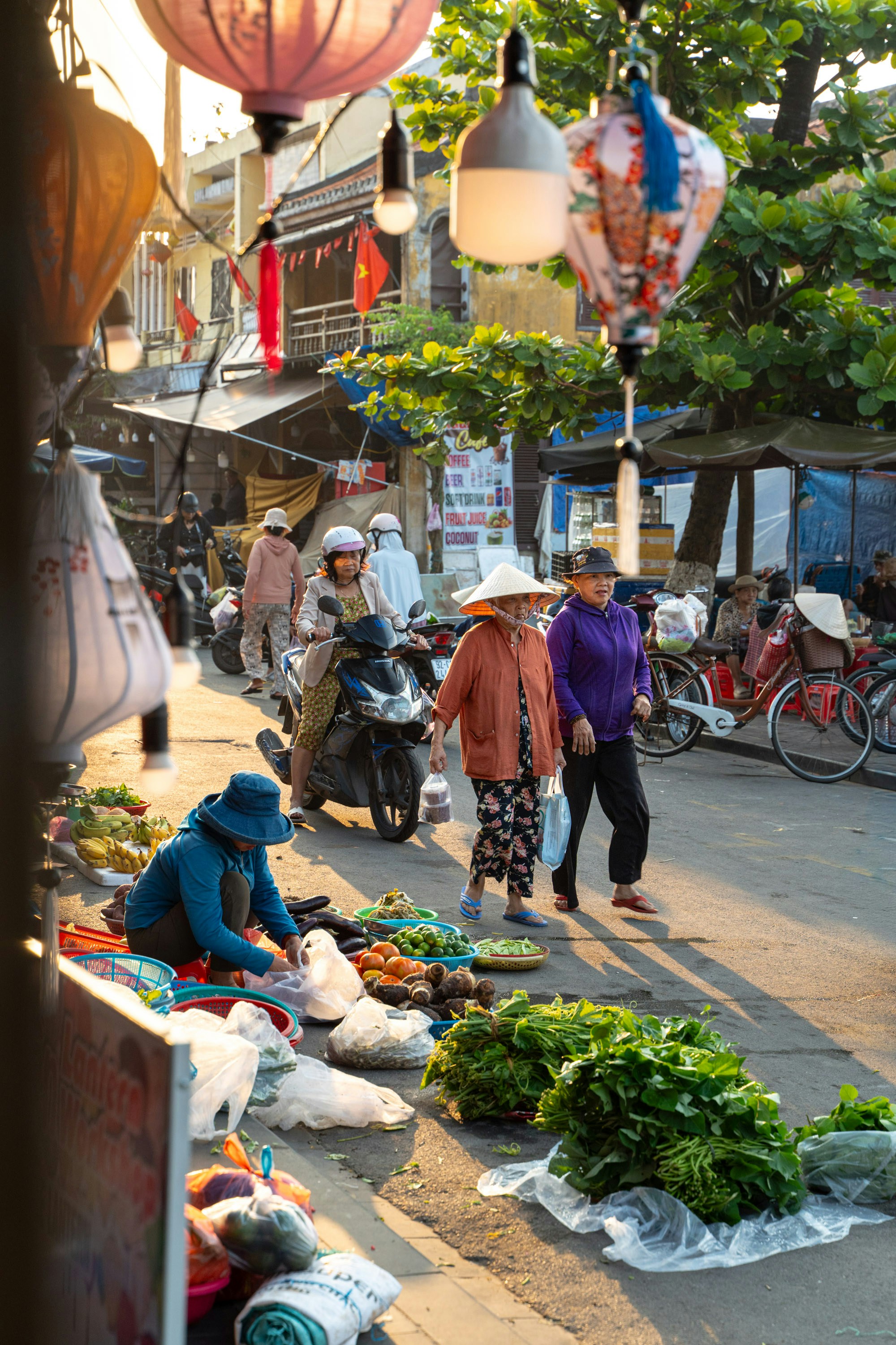 People selling produce at a sunny outdoor market.