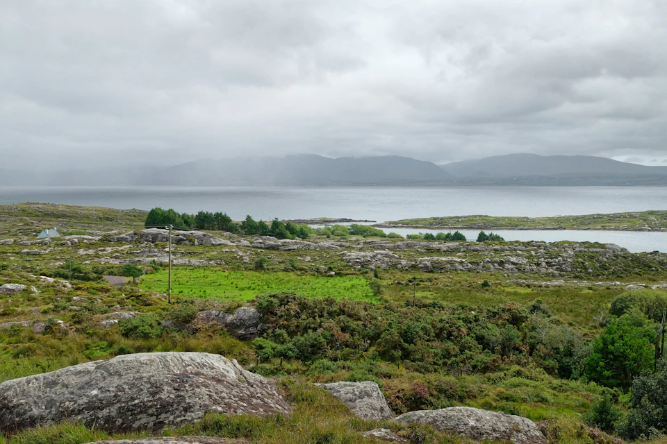 Serene ocean landscape with rocky foreground and distant clouds in soft, diffused light