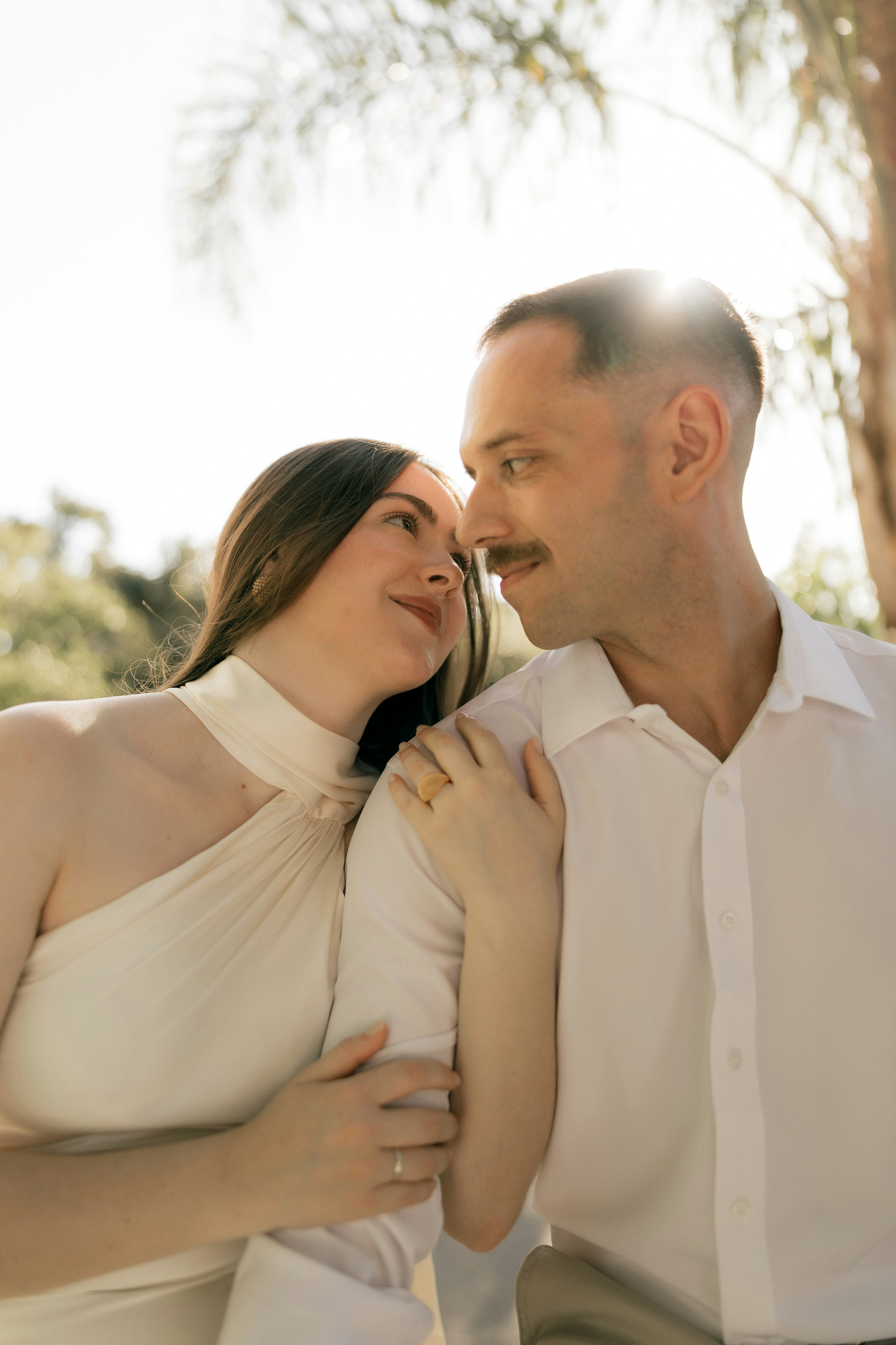 Pareja mirándose con cariño al aire libre con la luz del sol brillando