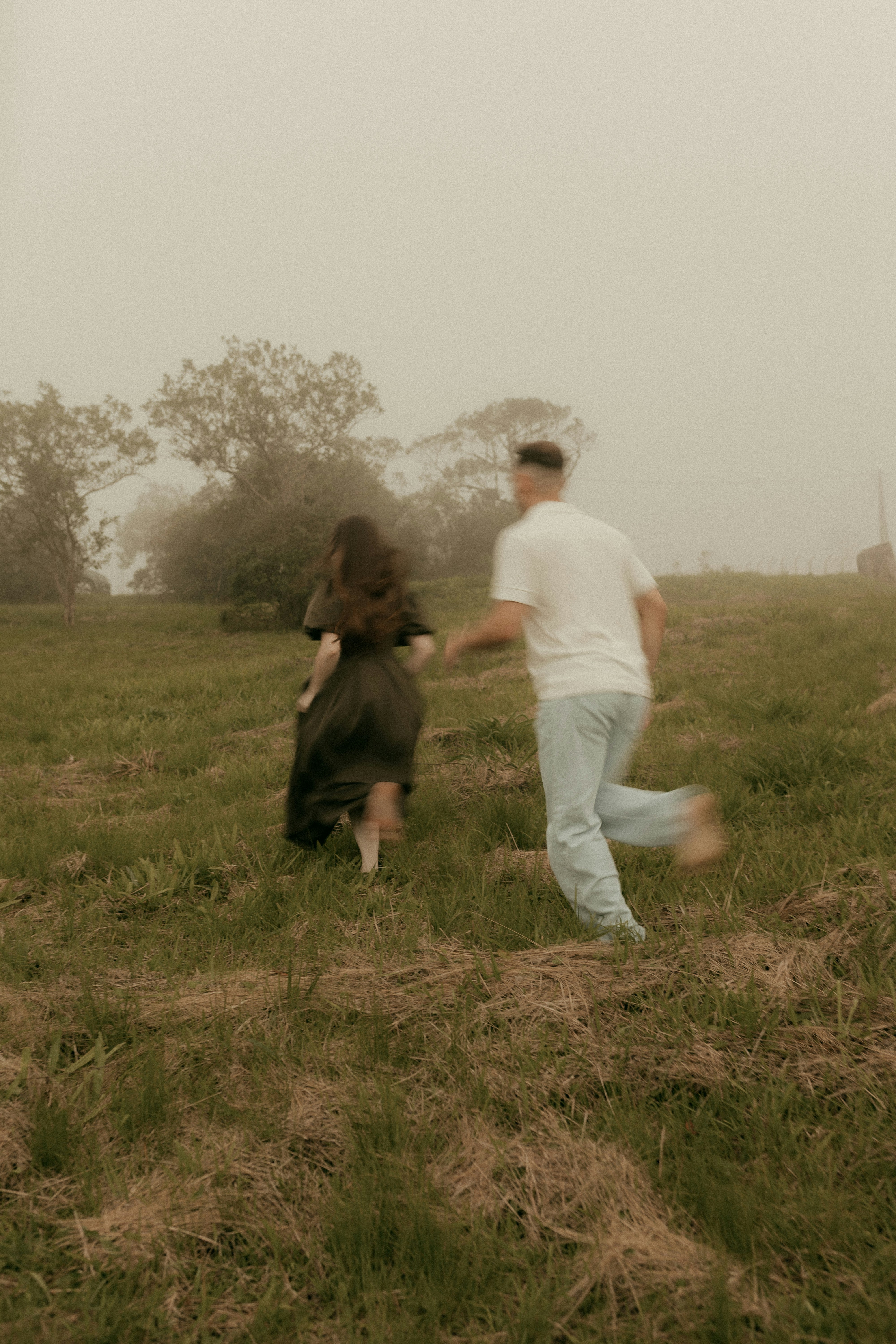 Couple running through a grassy field in fog