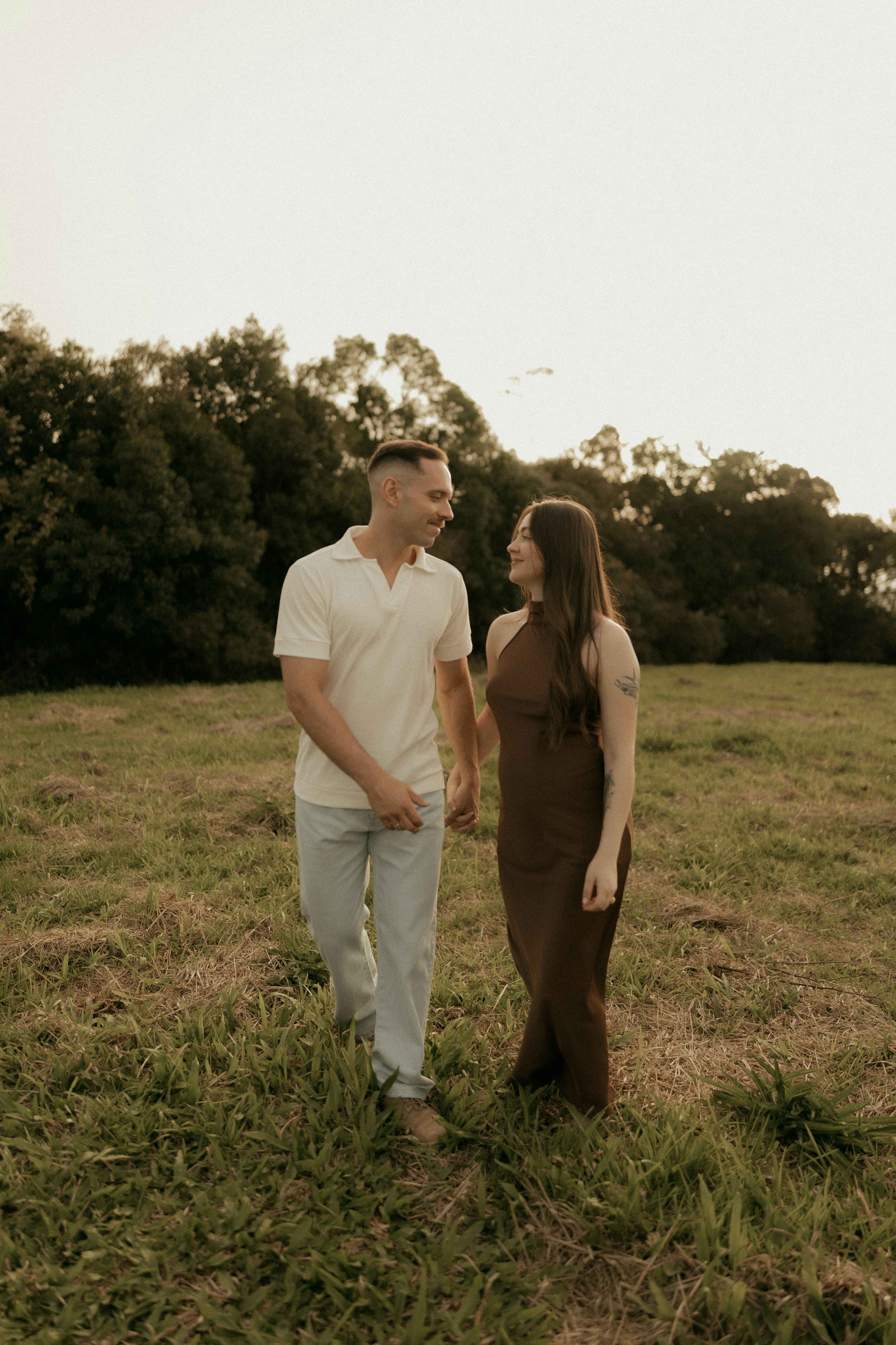 Couple walking hand-in-hand in a grassy field