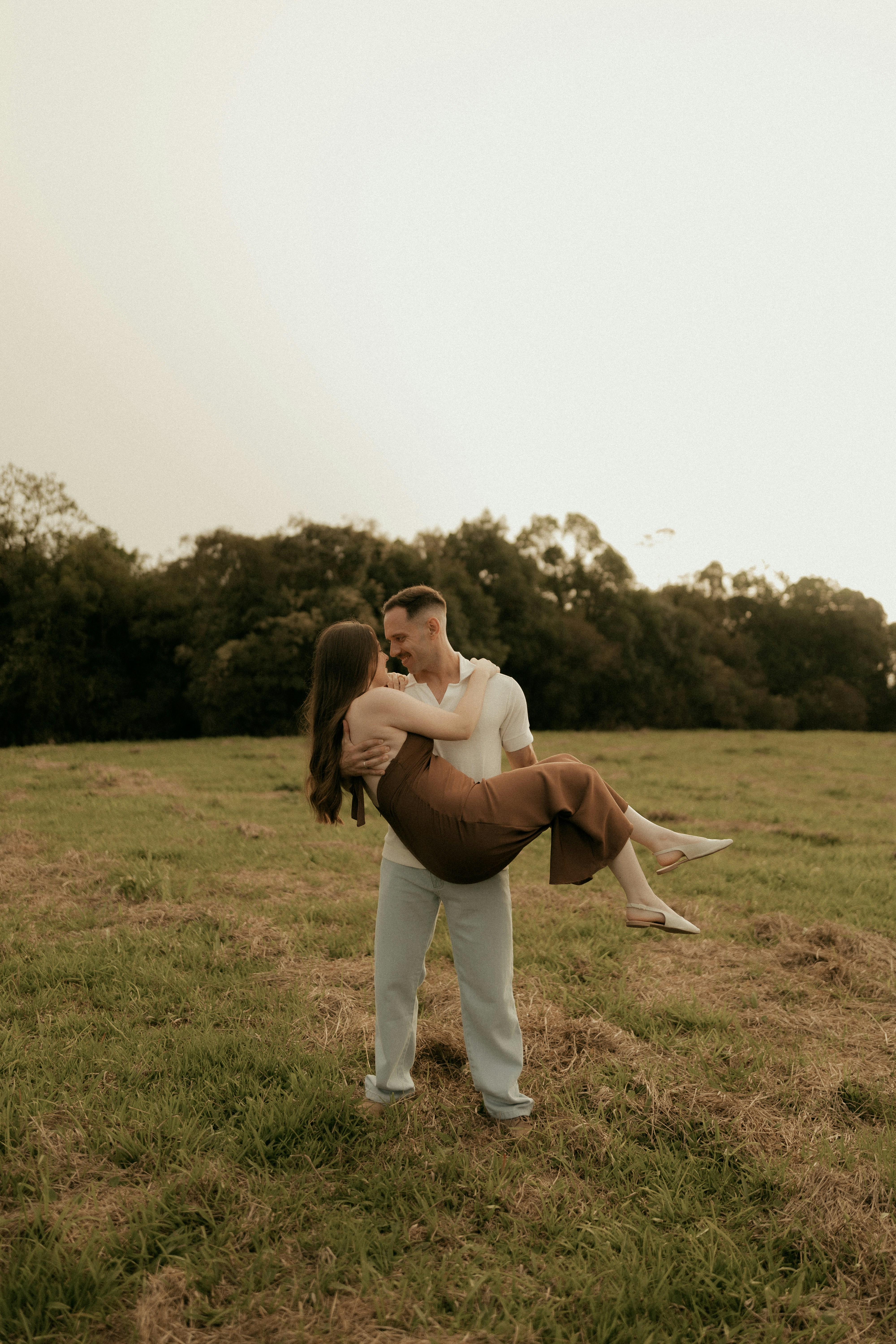 Man carrying woman in a grassy field