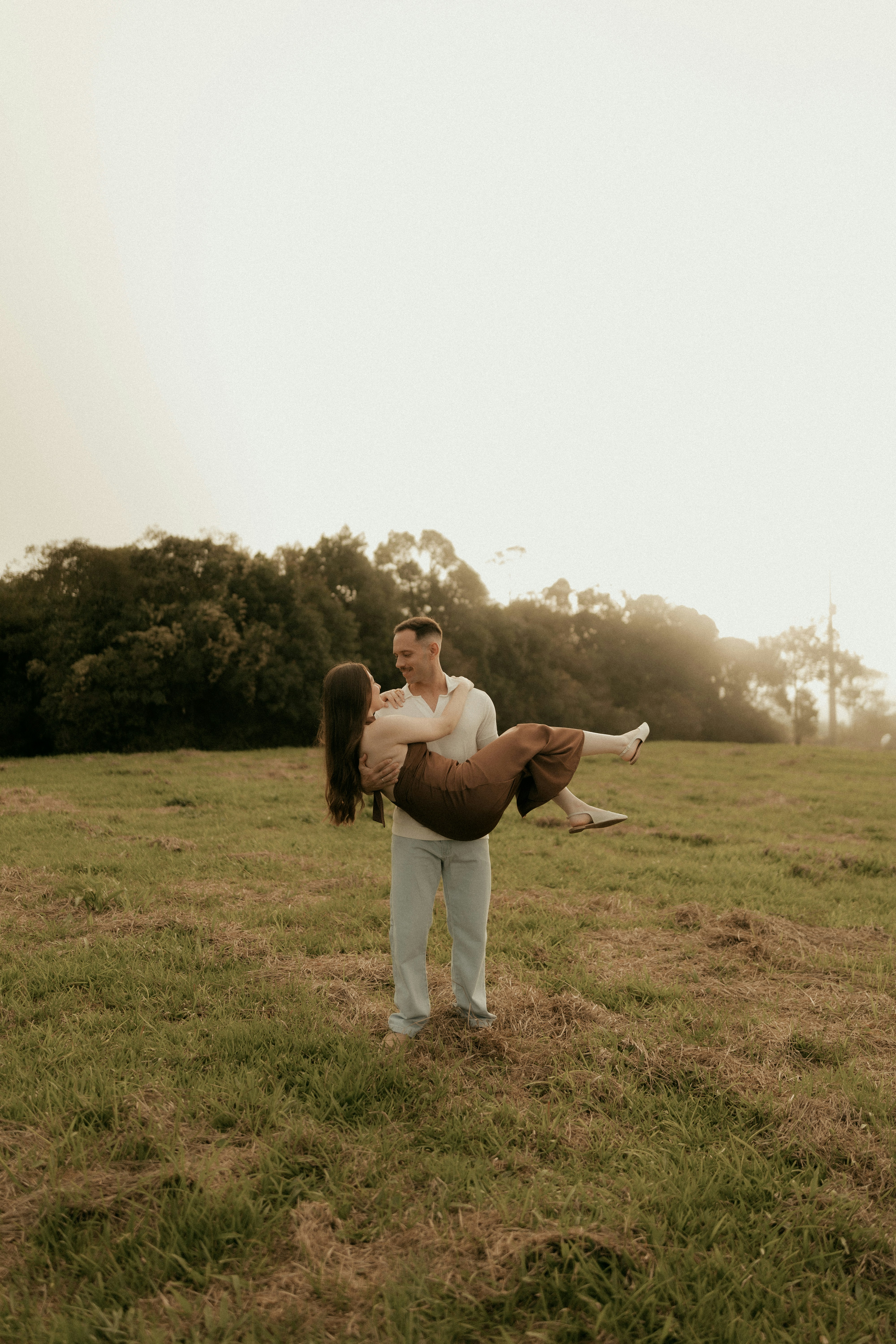 Man carrying woman in a grassy field