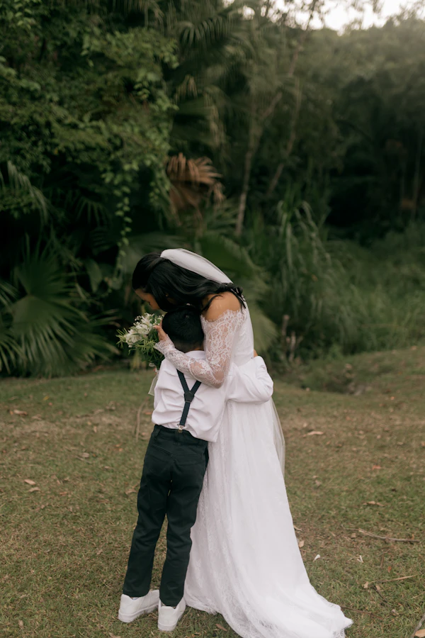 Bride hugging a young boy in a garden