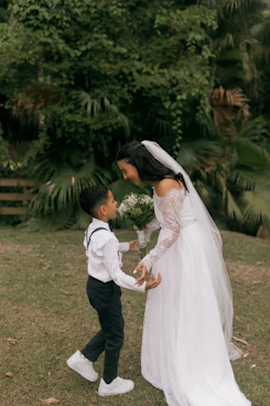 Bride and ring bearer share a tender moment outdoors.