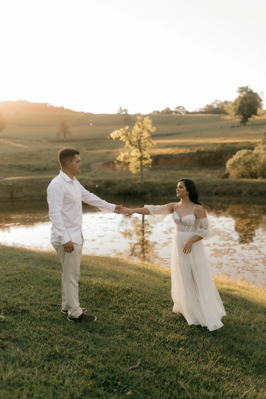 Couple holding hands by a lake at sunset