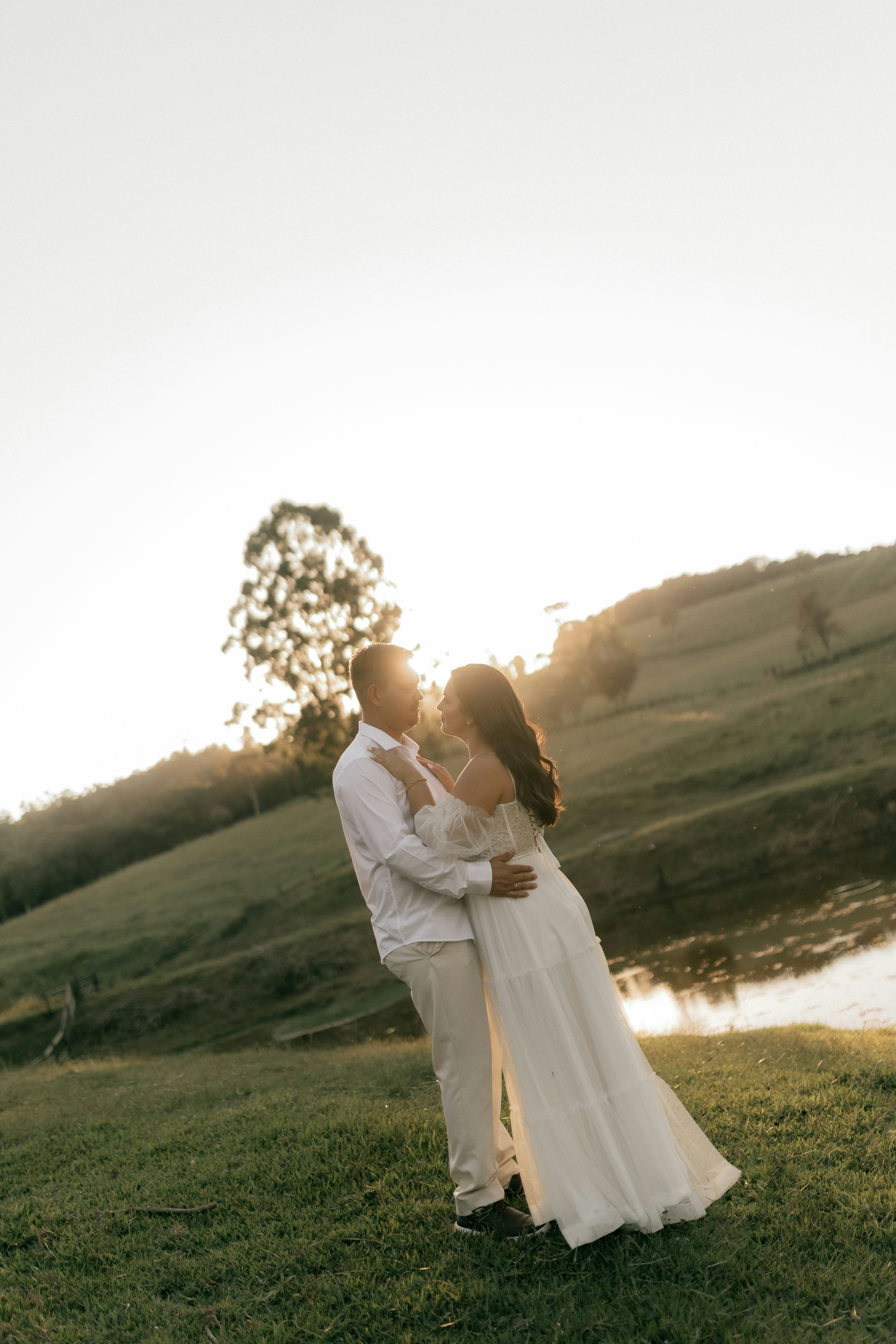 Couple embracing in a grassy field at sunset