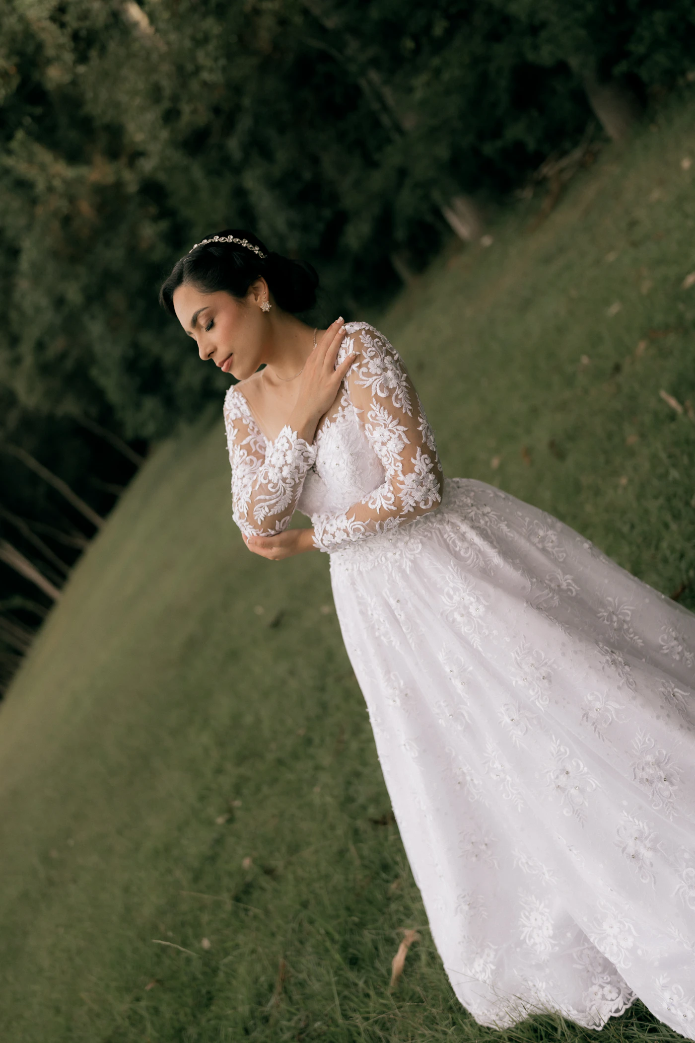 Best lace wedding dresses for summer outdoor ceremonies — A bride in a delicate lace A-line gown stands in a sunlit garden.
