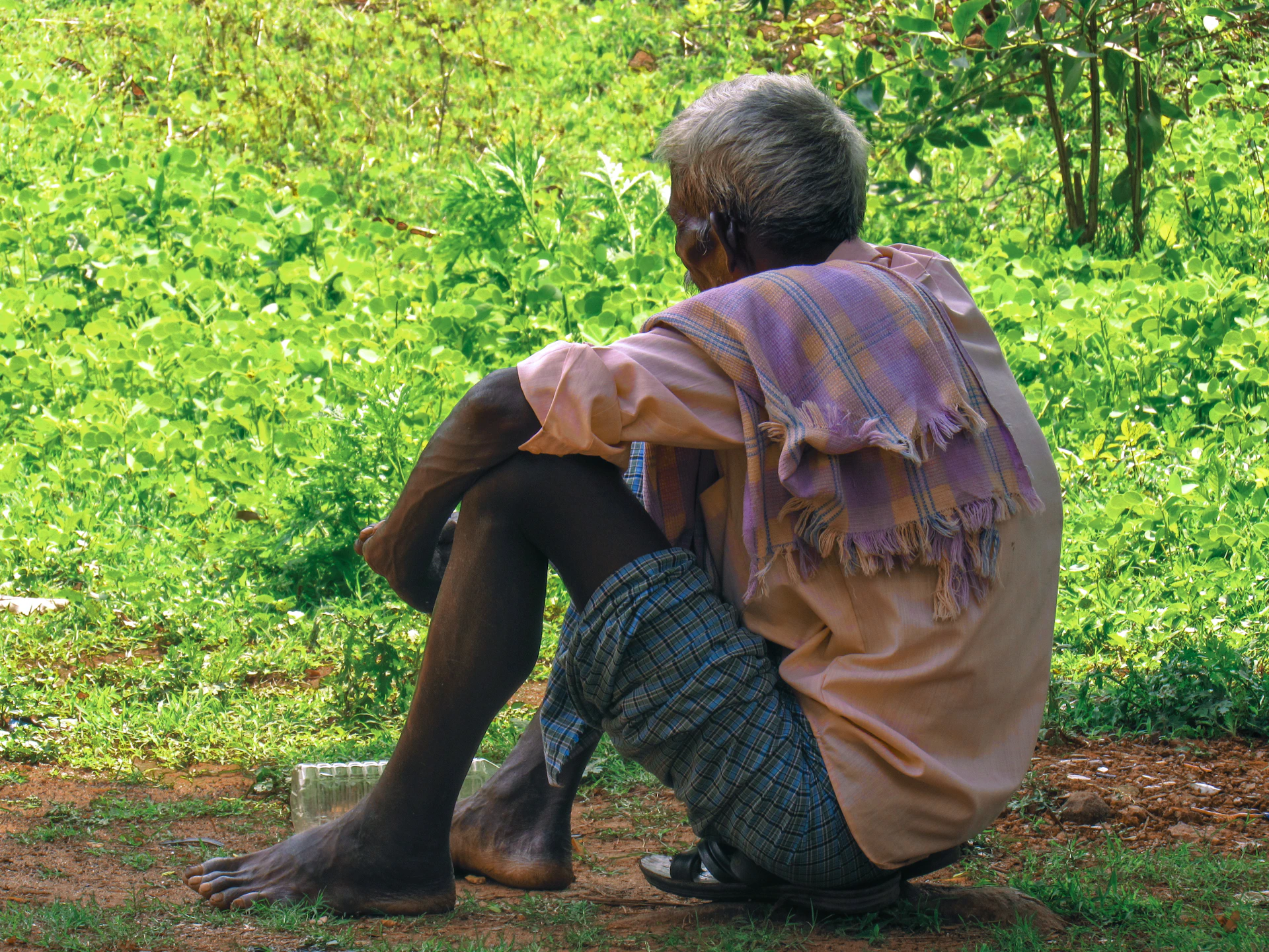 Elderly man sitting outdoors, looking away