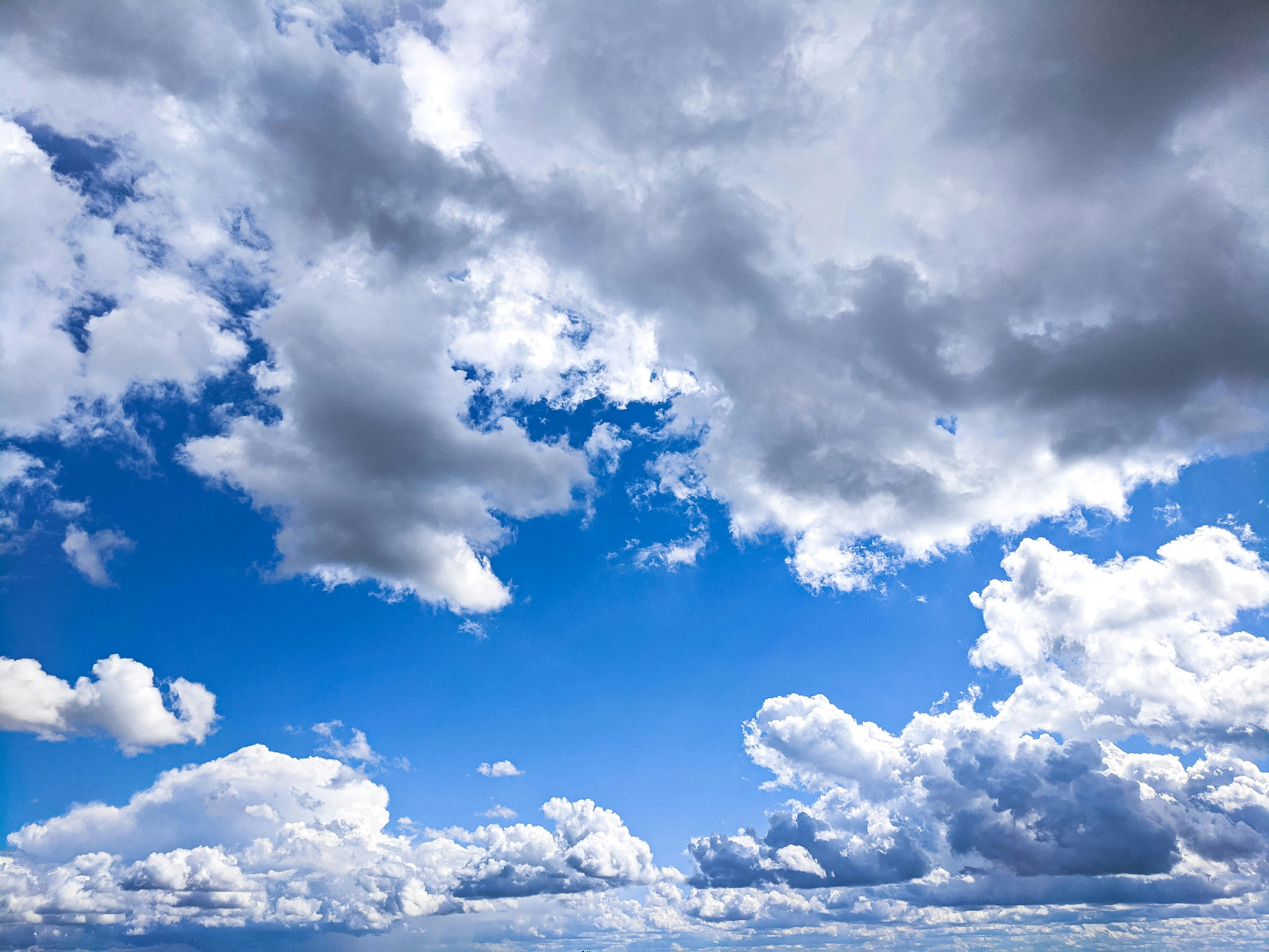 Fluffy white clouds drift across a bright blue sky.