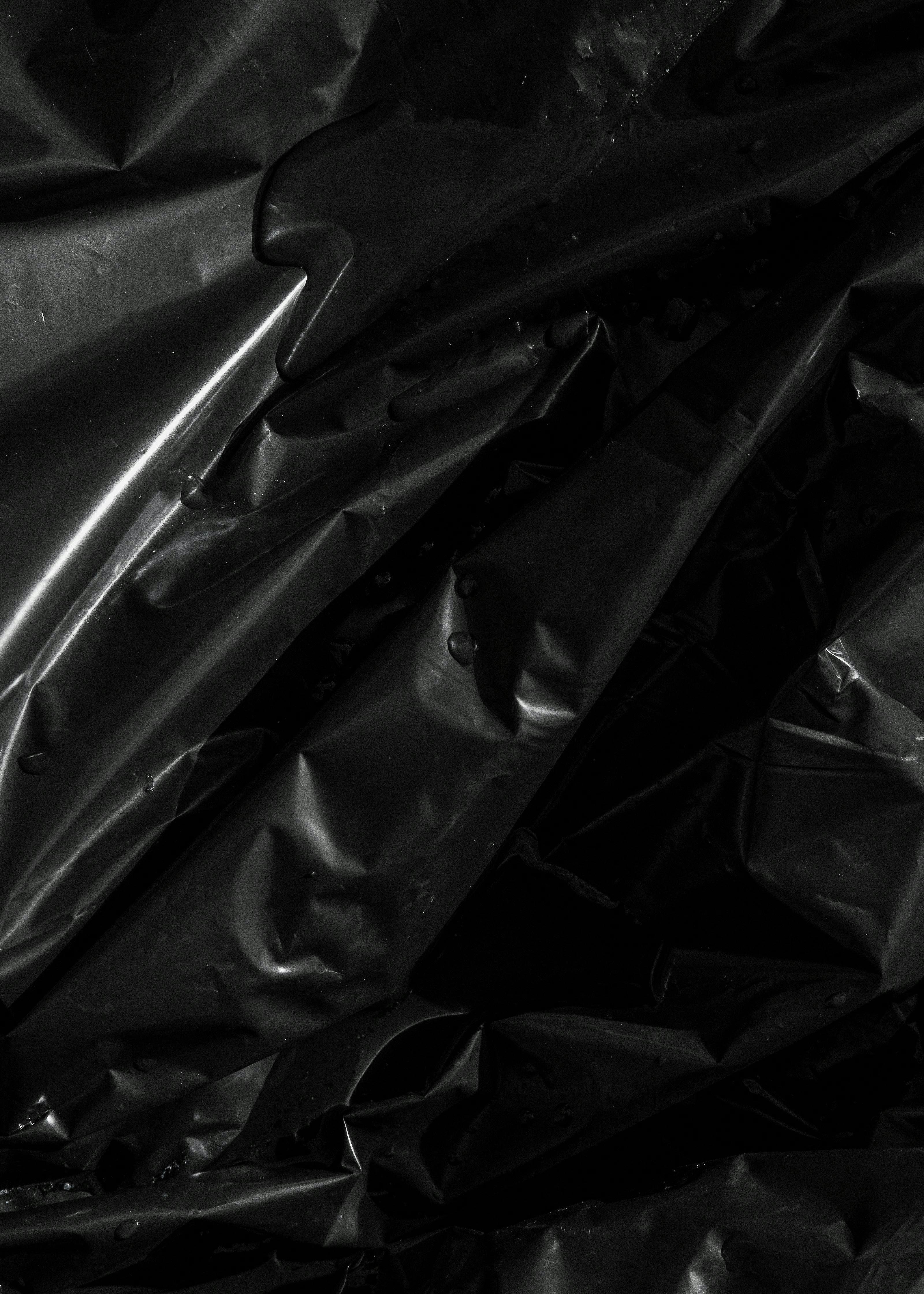 Plastica nera lucida e accartocciata con gocce d'acqua