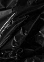 Shiny black crumpled plastic with water droplets