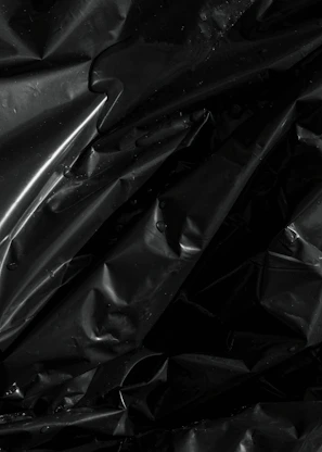 Shiny black crumpled plastic with water droplets