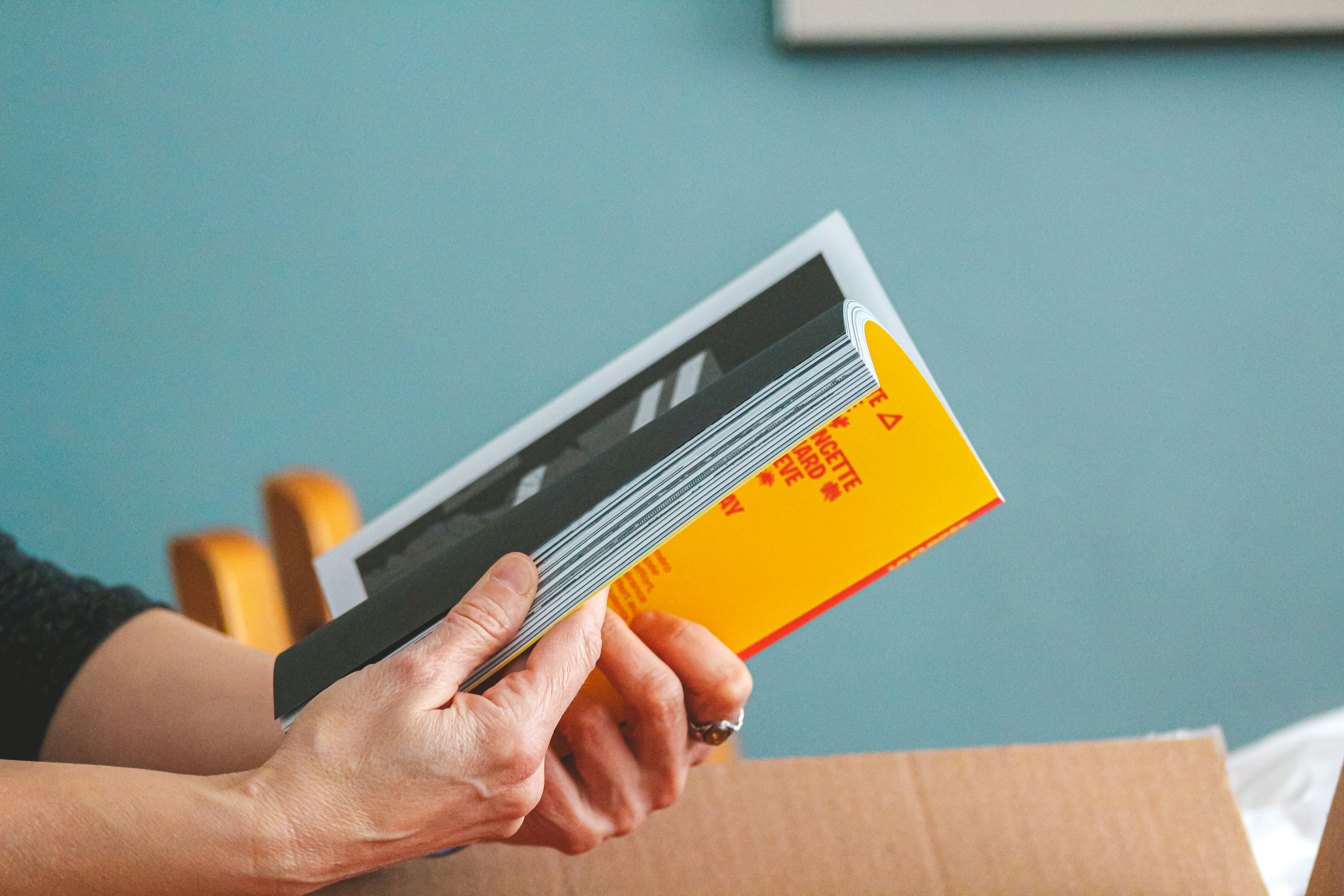 Hands holding a book with a yellow cover.