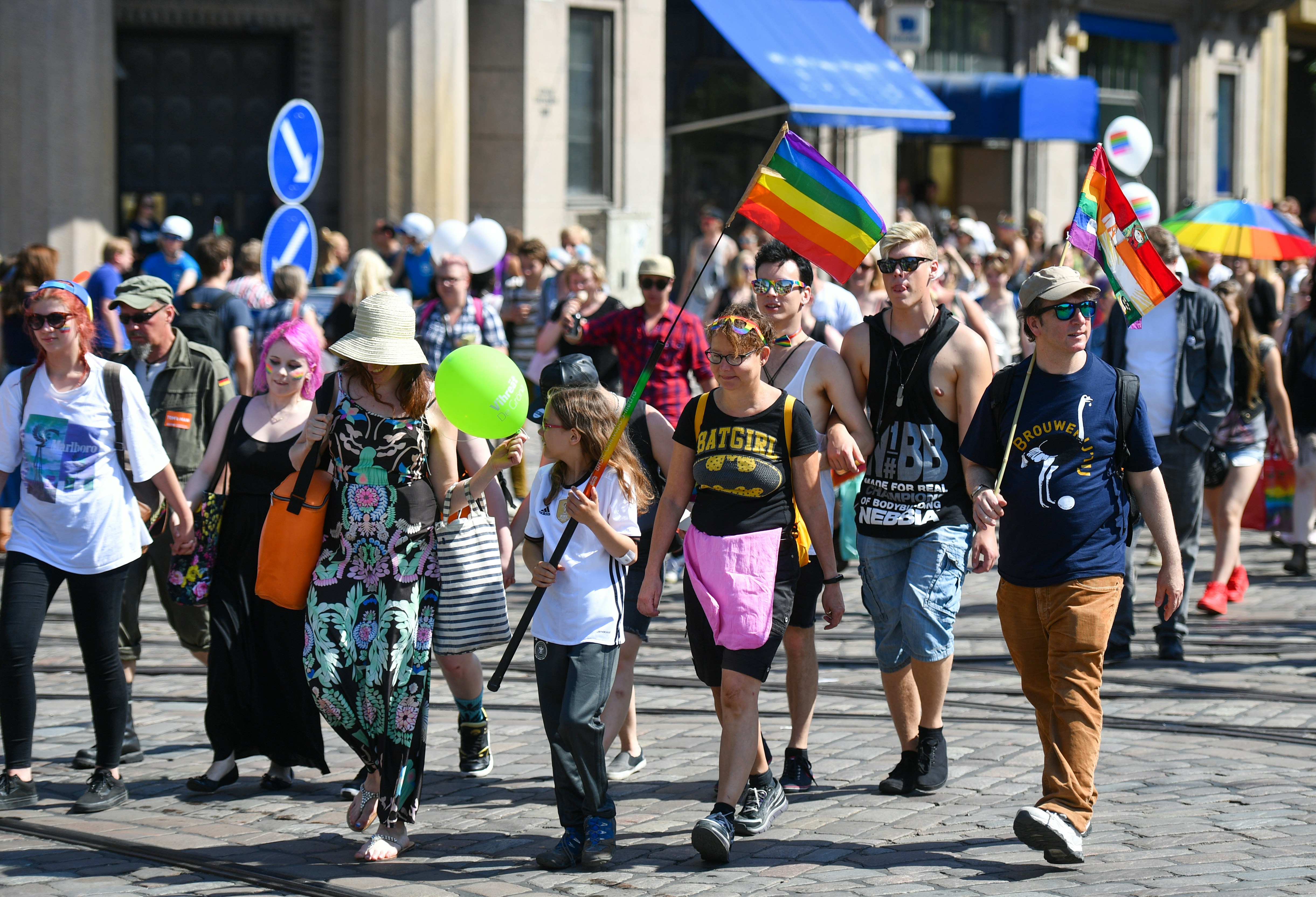 A vibrant LGBTQ pride parade in the city center of Helsinki, with colorful flags, balloons, and joyful people marching together in celebration of diversity, equality, and inclusion.