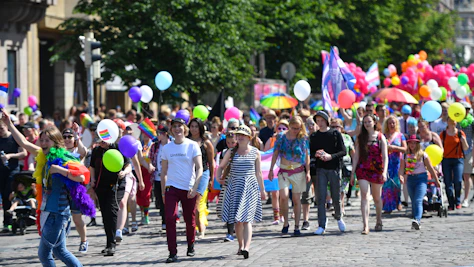 People celebrating at a pride parade with balloons and flags