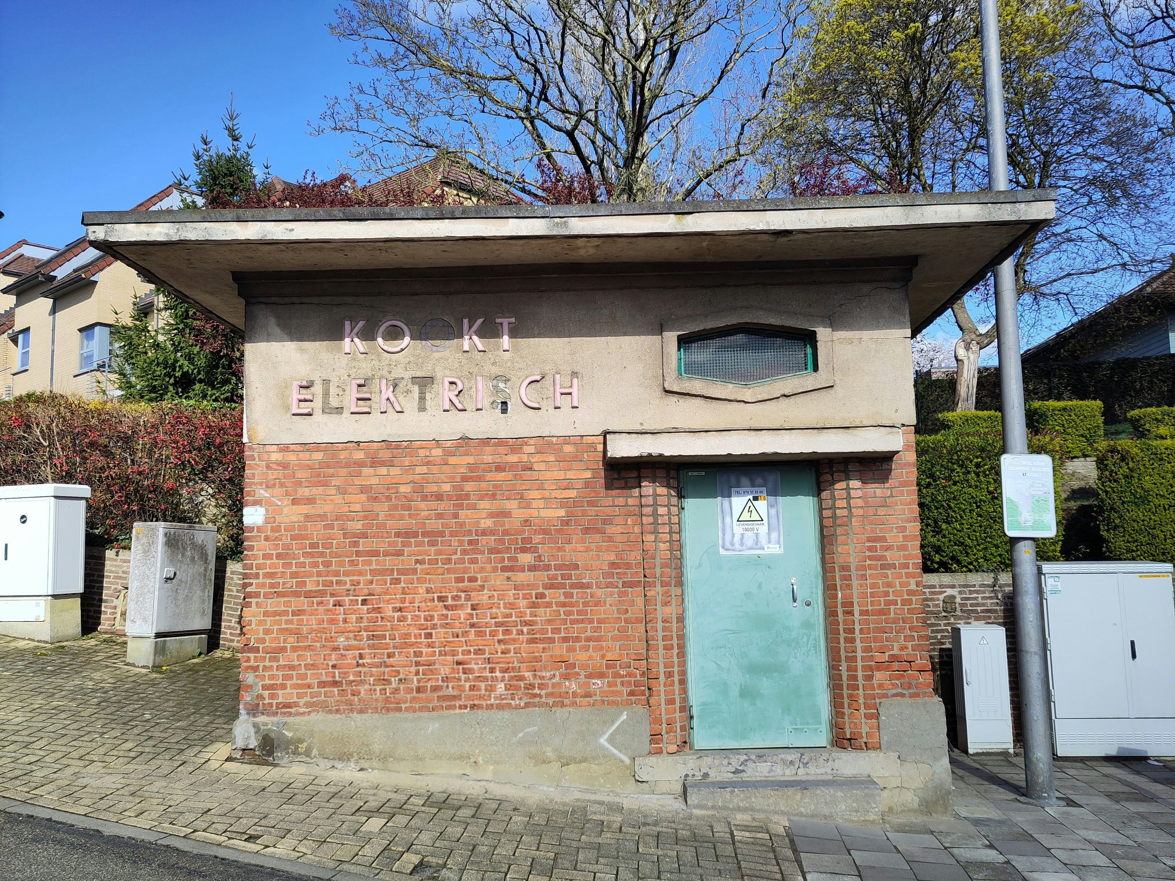 Petit bâtiment en brique avec porte verte et panneau