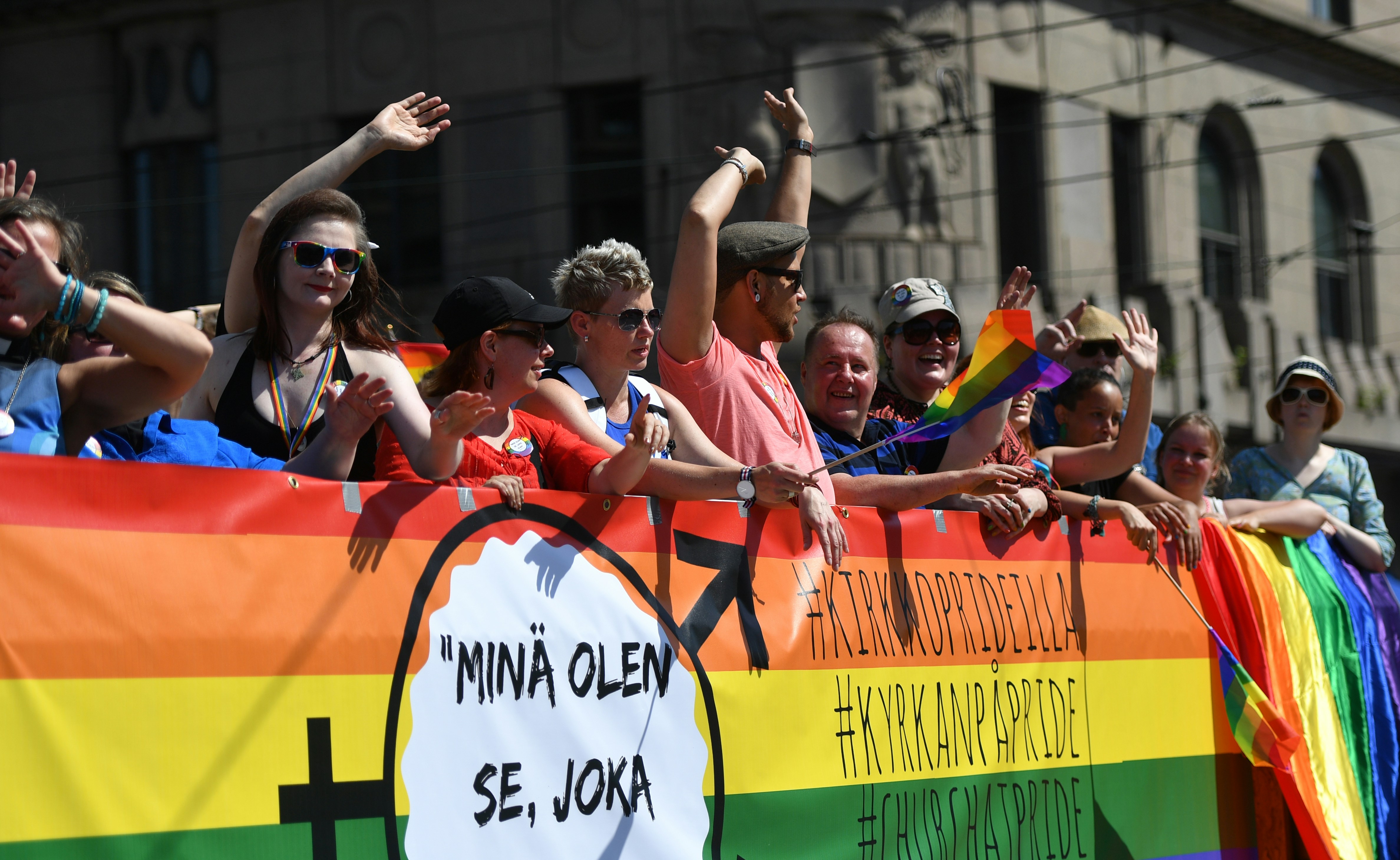 A vibrant LGBTQ pride parade in the city center of Helsinki, with colorful flags, balloons, and joyful people marching together in celebration of diversity, equality, and inclusion.