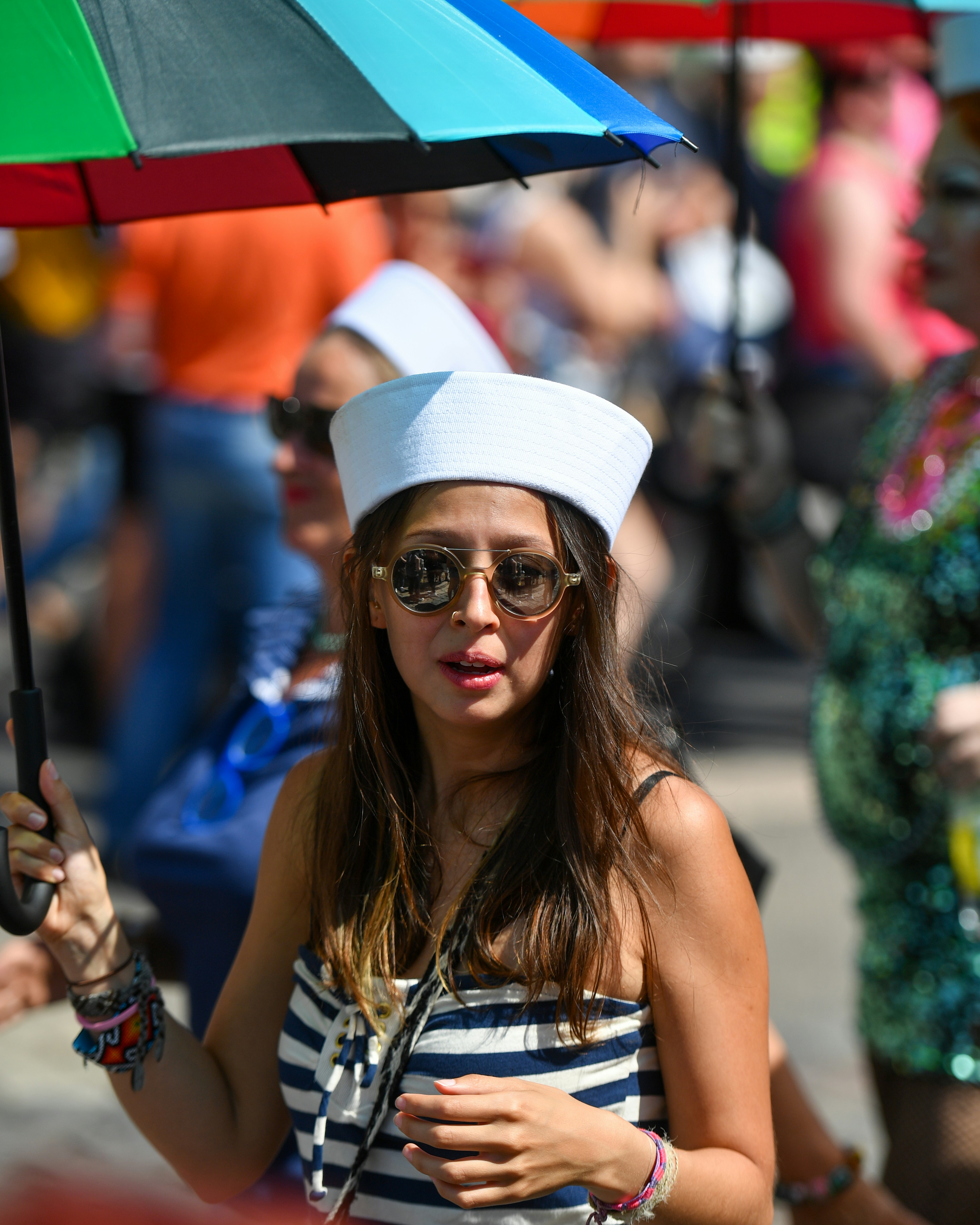 Femme au chapeau de marin tenant un parapluie coloré lors d’un défilé