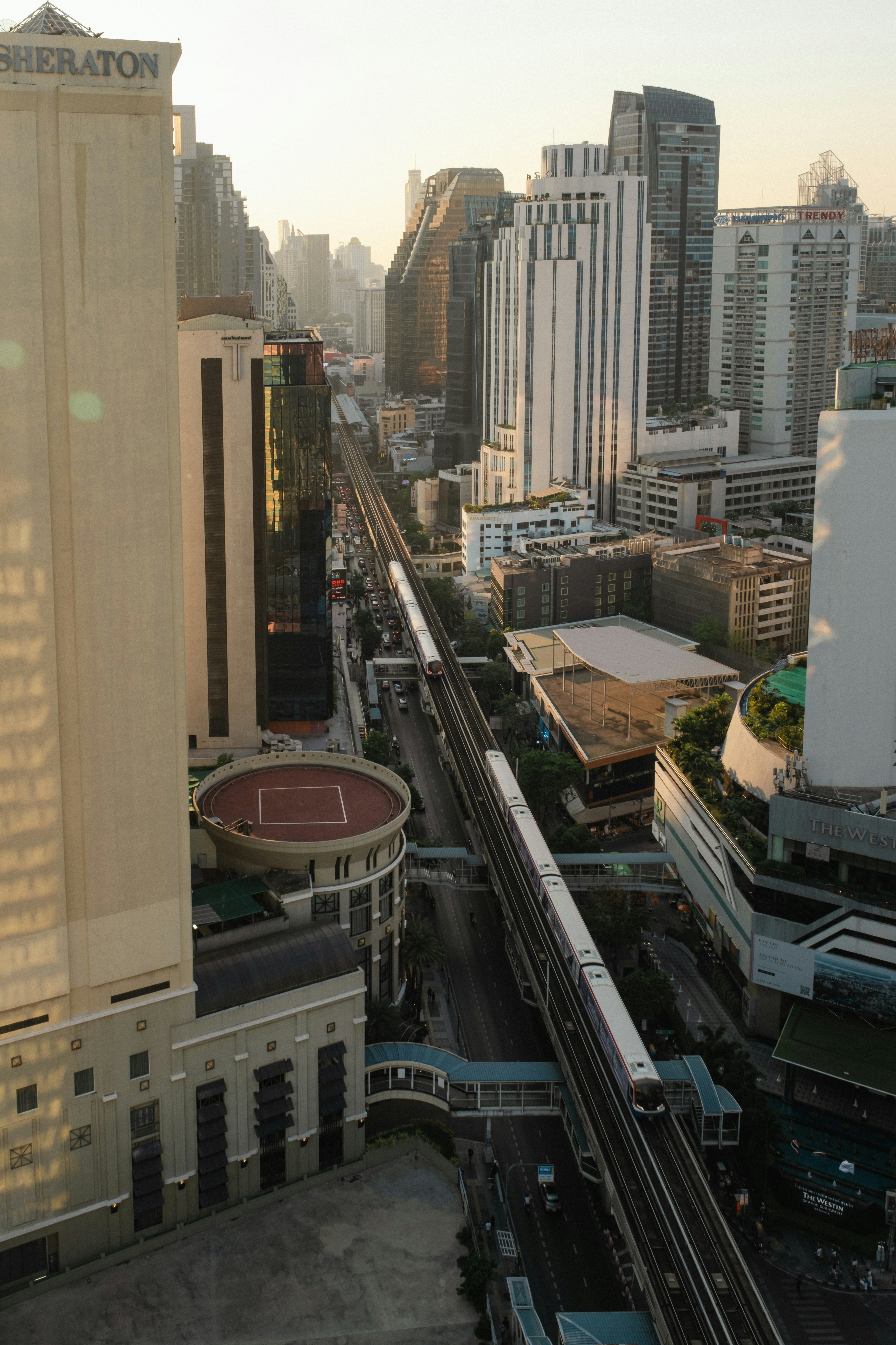 Elevated train tracks run through a modern cityscape.
