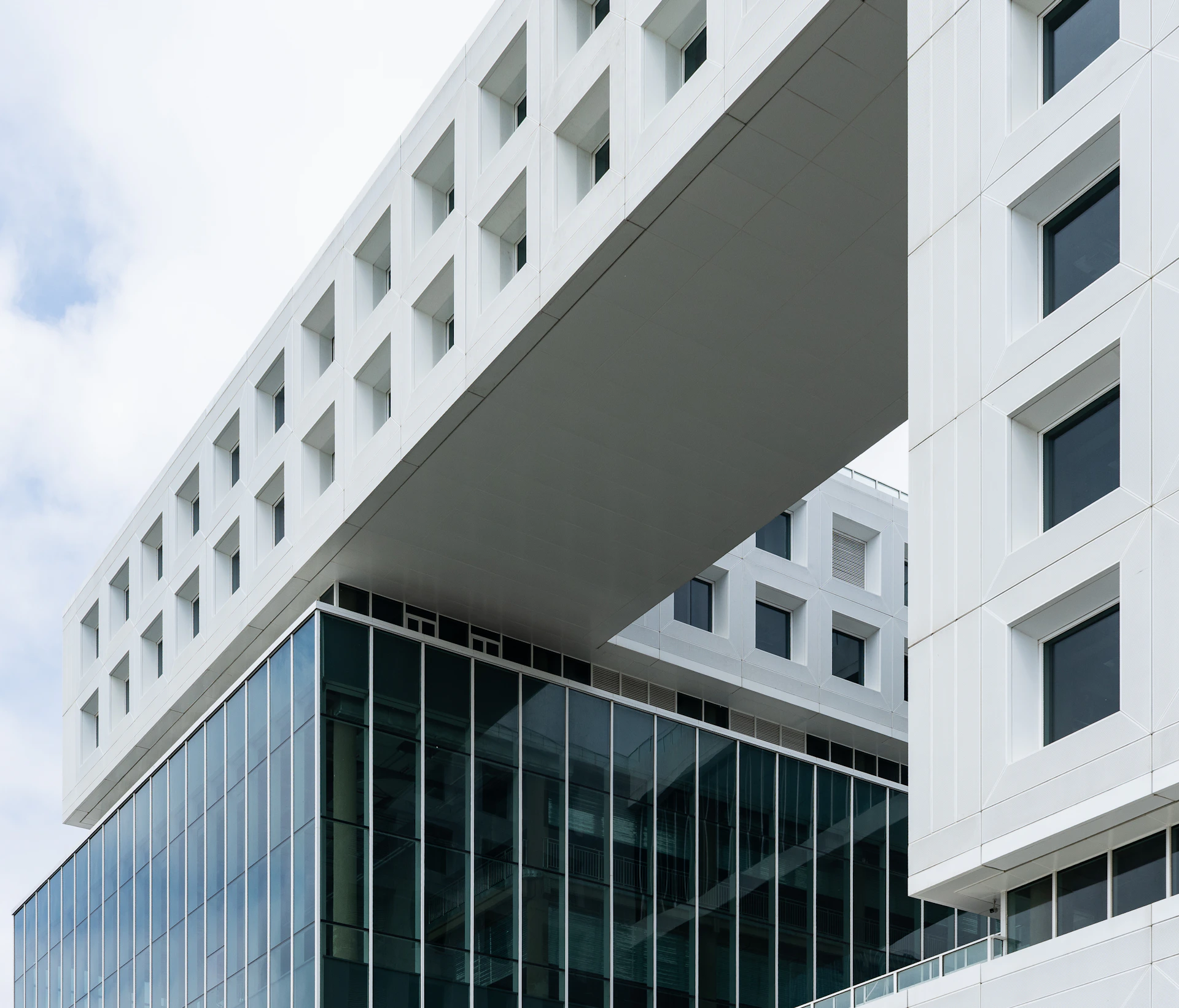 Modern white building with glass facade and cantilevered section.