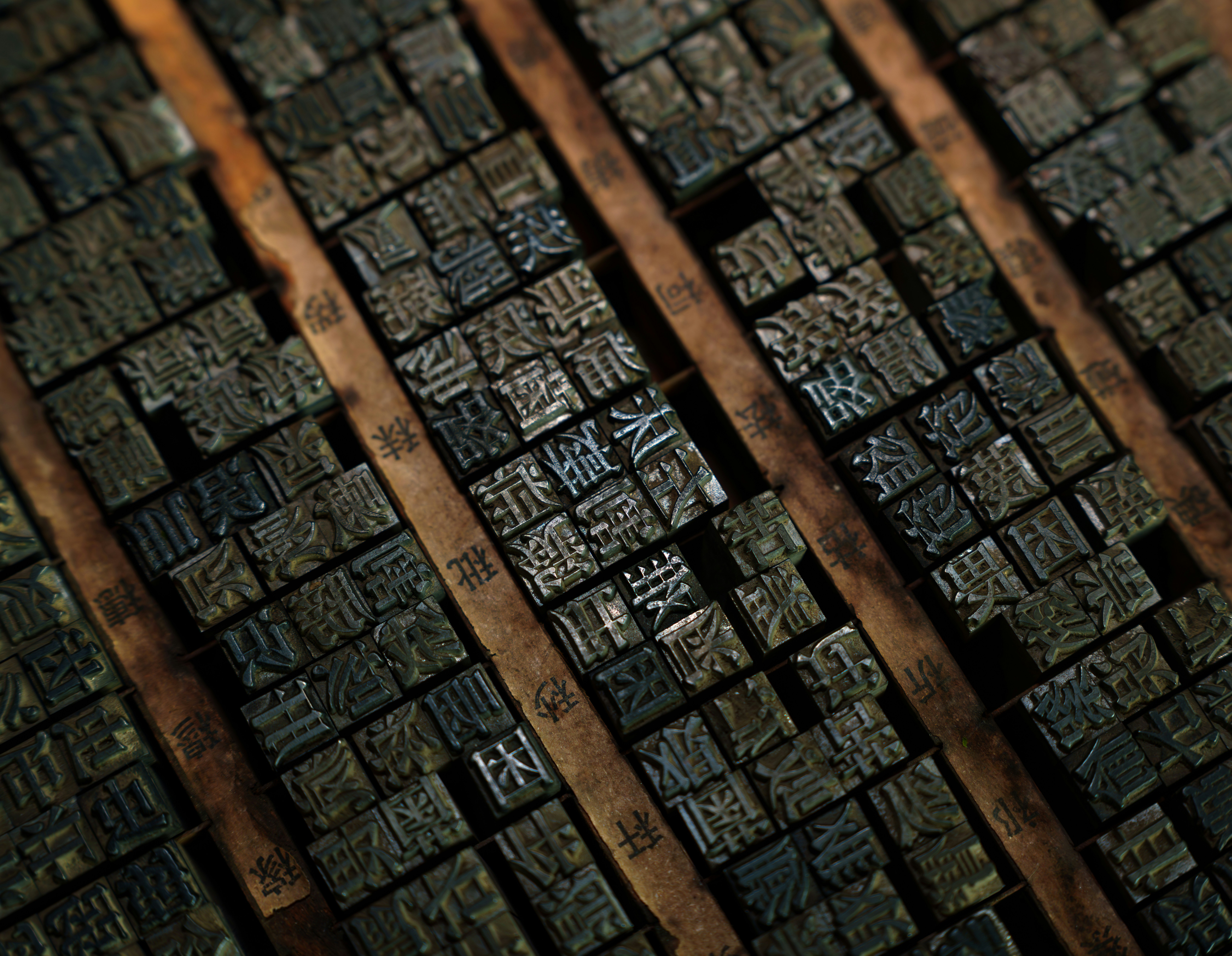 Close-up of antique wooden letterpress type blocks, showing the relief surface and worn character of hand-carved or cast printing blocks