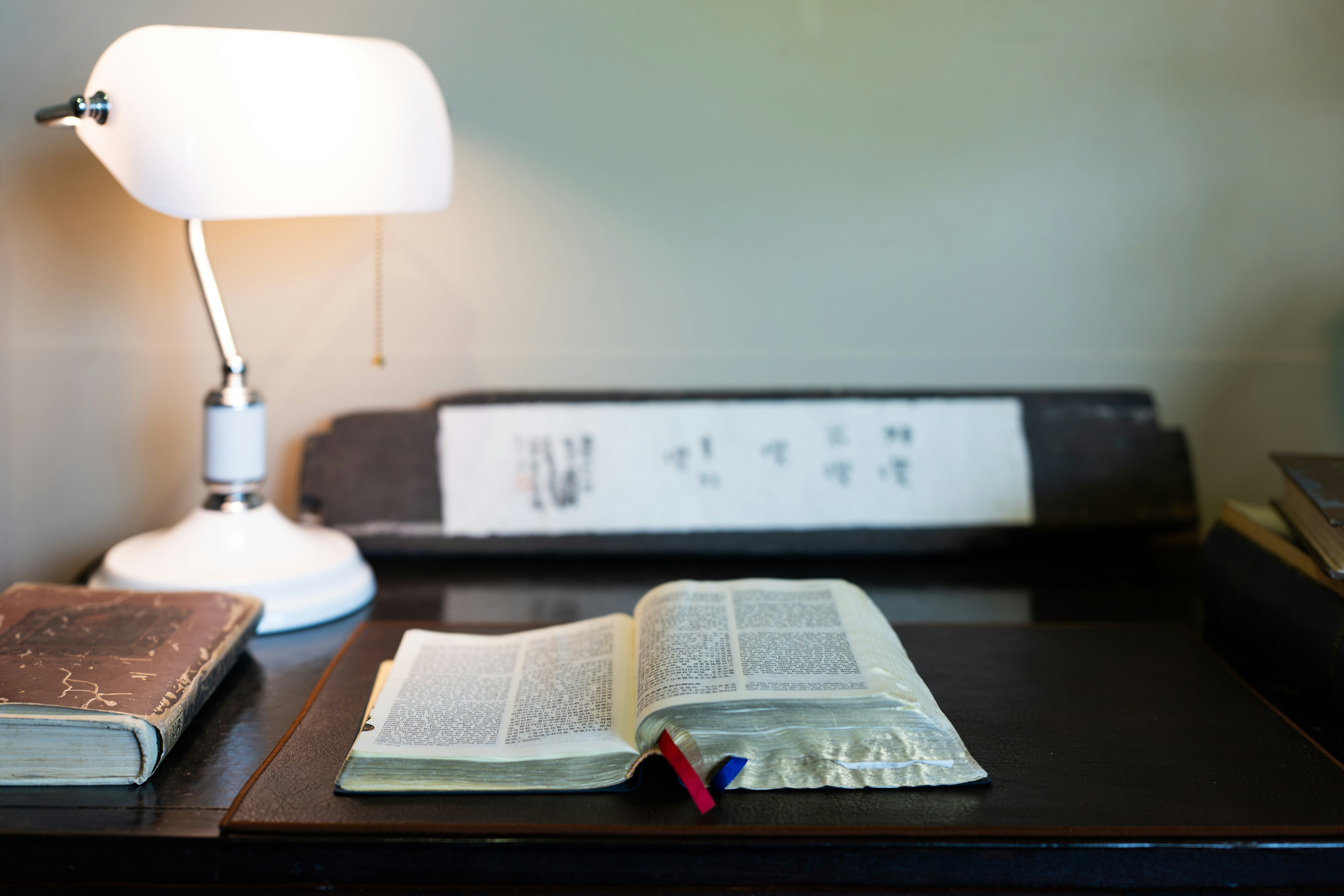 An open book rests on a desk with a lamp.