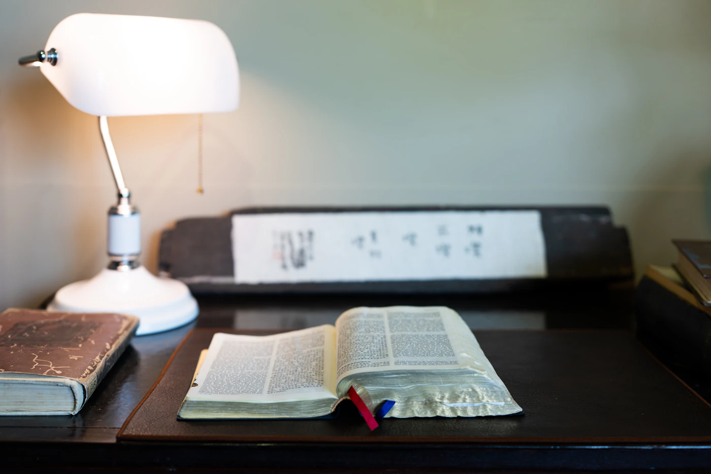 A tidy desk with an open book, a lamp and warm light in a quiet study room