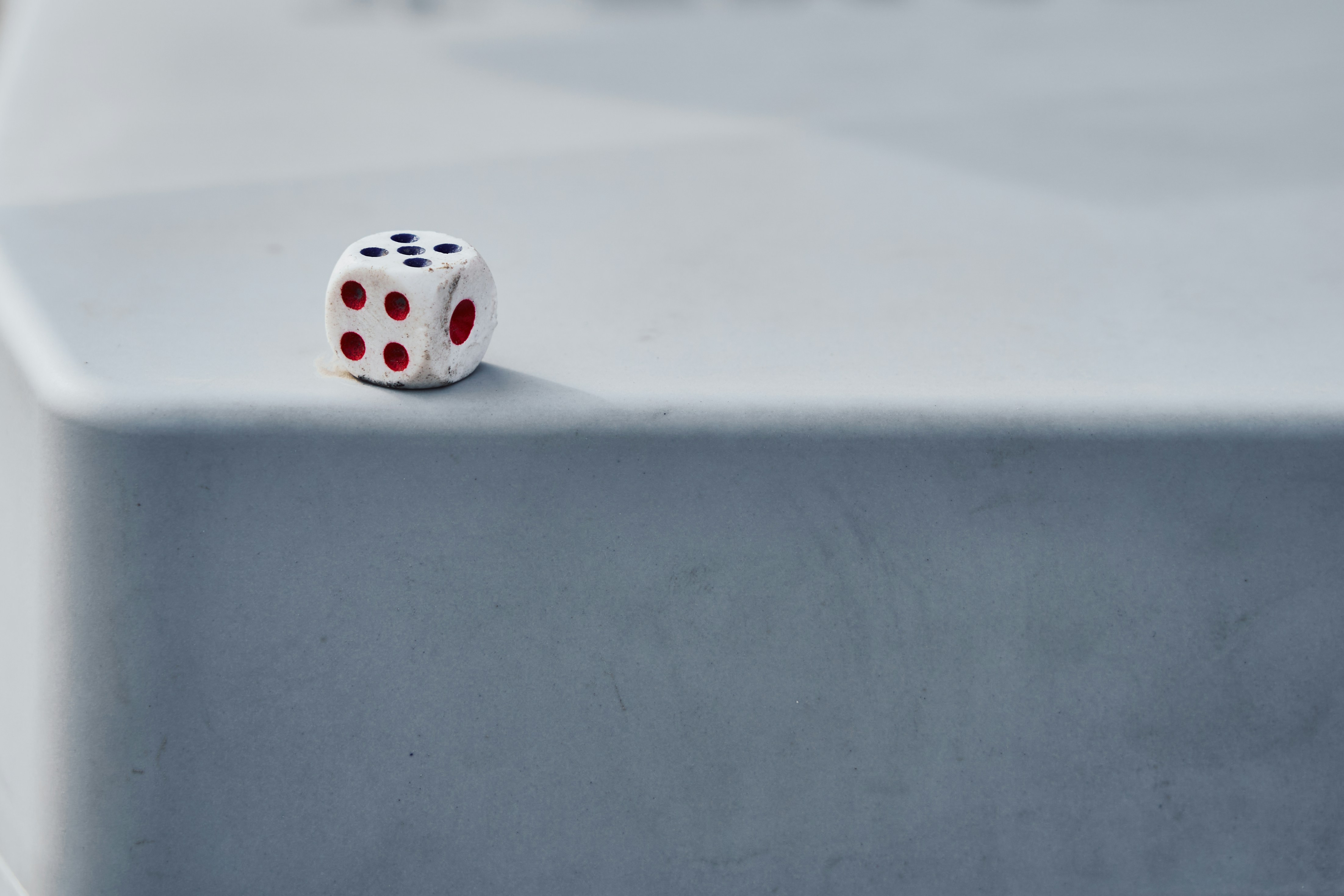 Un seul dé blanc repose sur une surface grise.