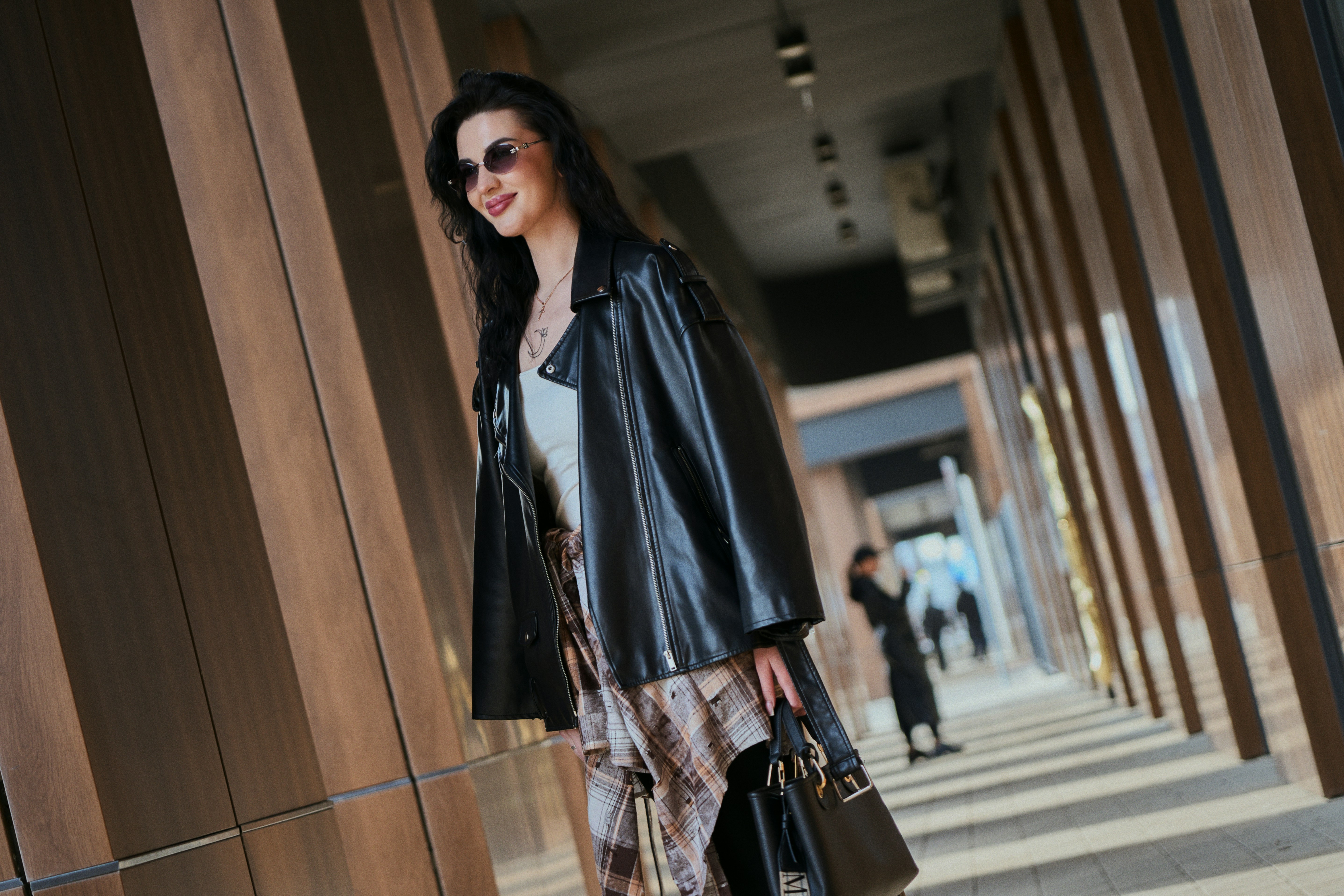 Woman in leather jacket walks down modern hallway