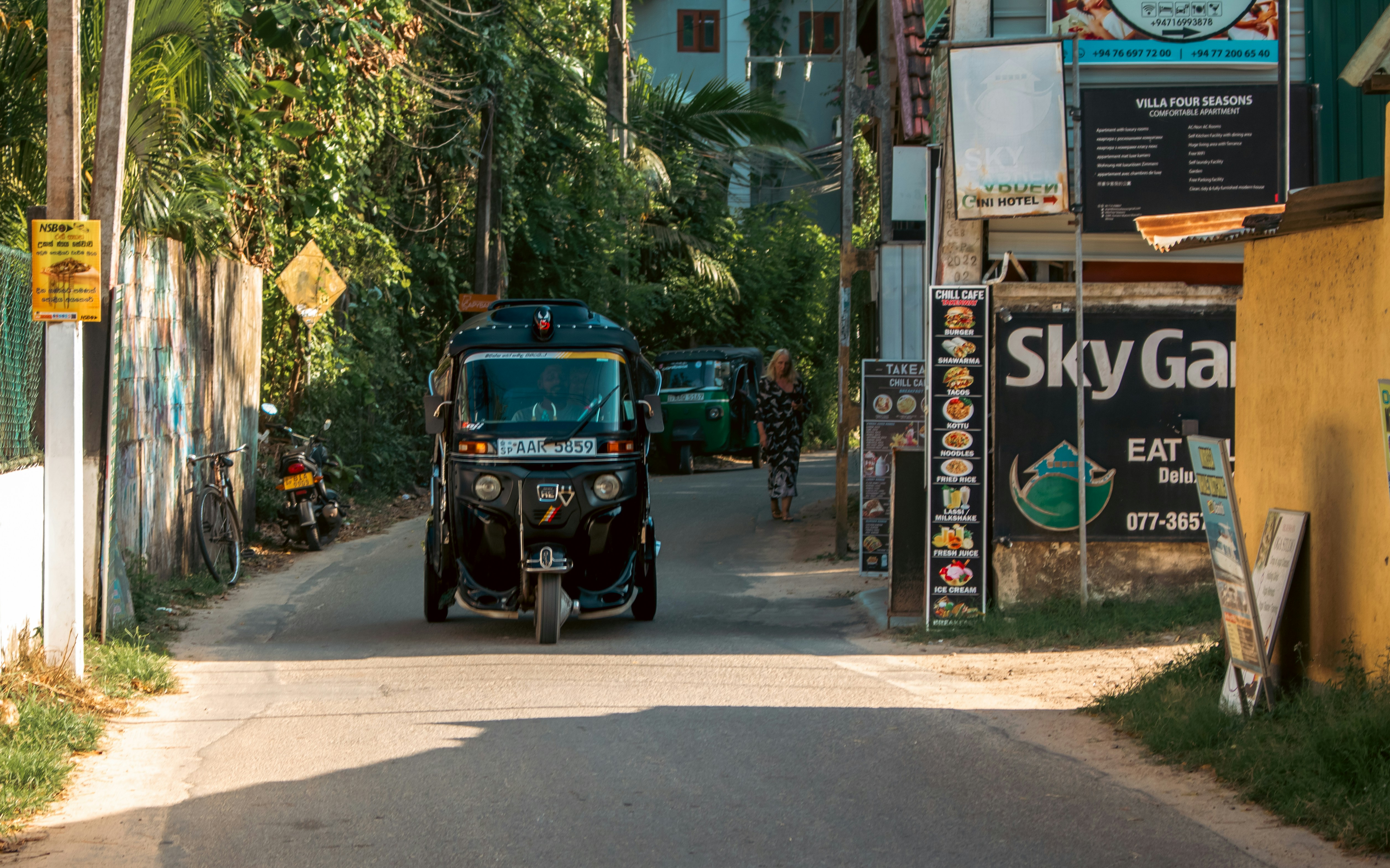 Tuk-tuk driving down a sunny street in Sri Lanka
