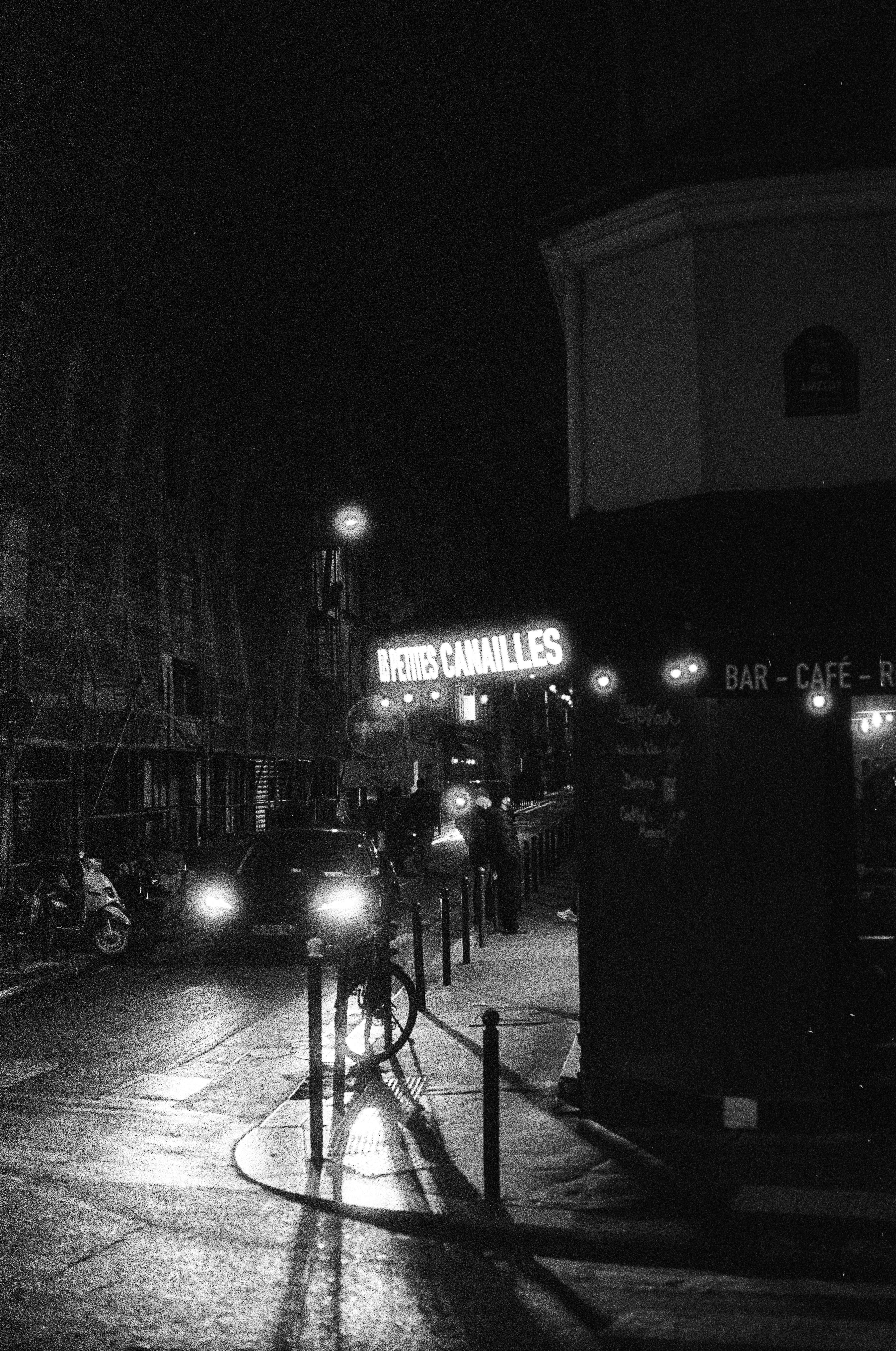 Pemandangan jalanan malam dengan rambu bercahaya dan lampu depan mobil.