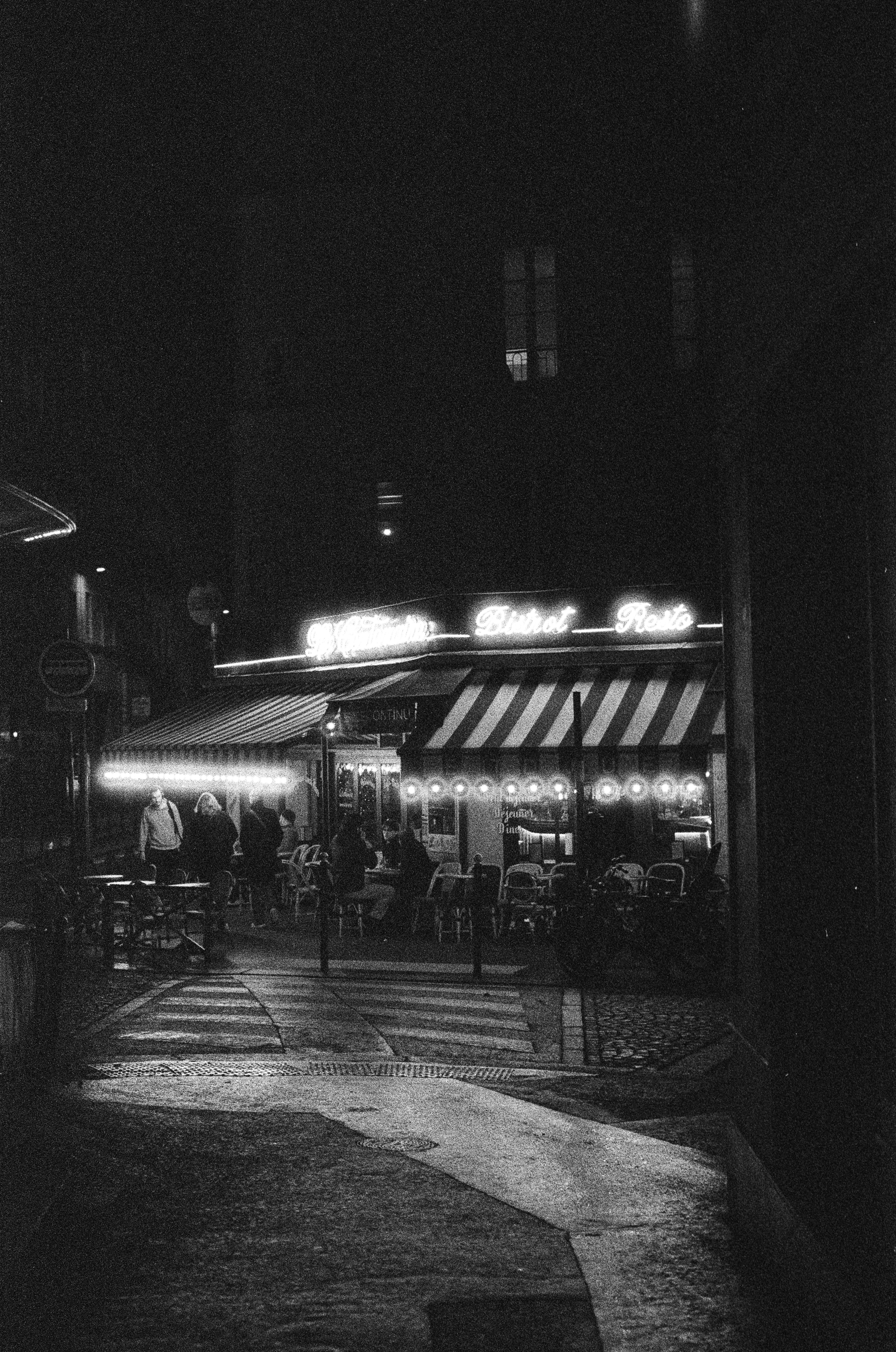 Pemandangan jalanan malam hari dengan kafe yang menyala.