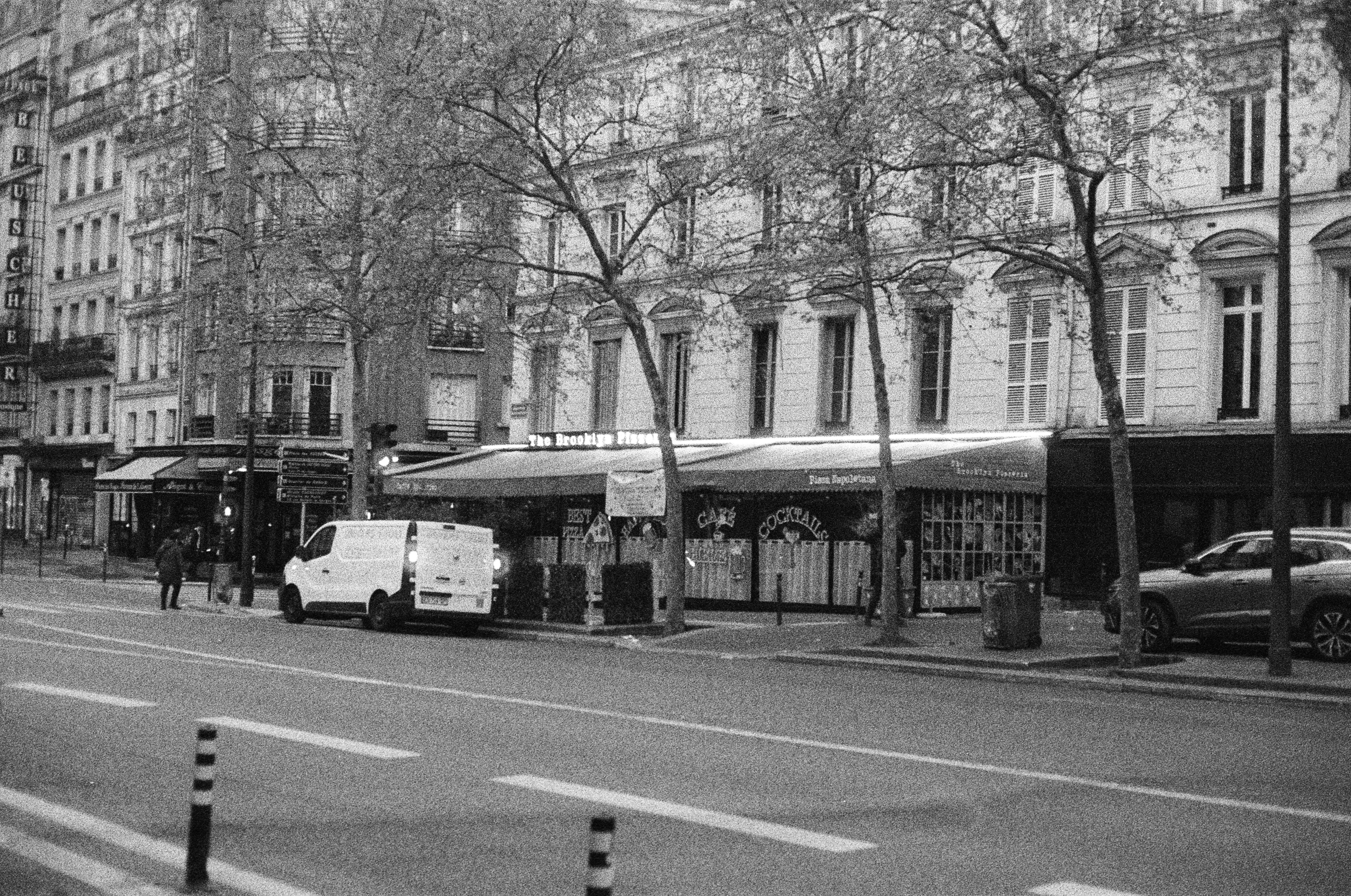 Pemandangan jalanan di paris dengan bangunan dan kendaraan yang diparkir.