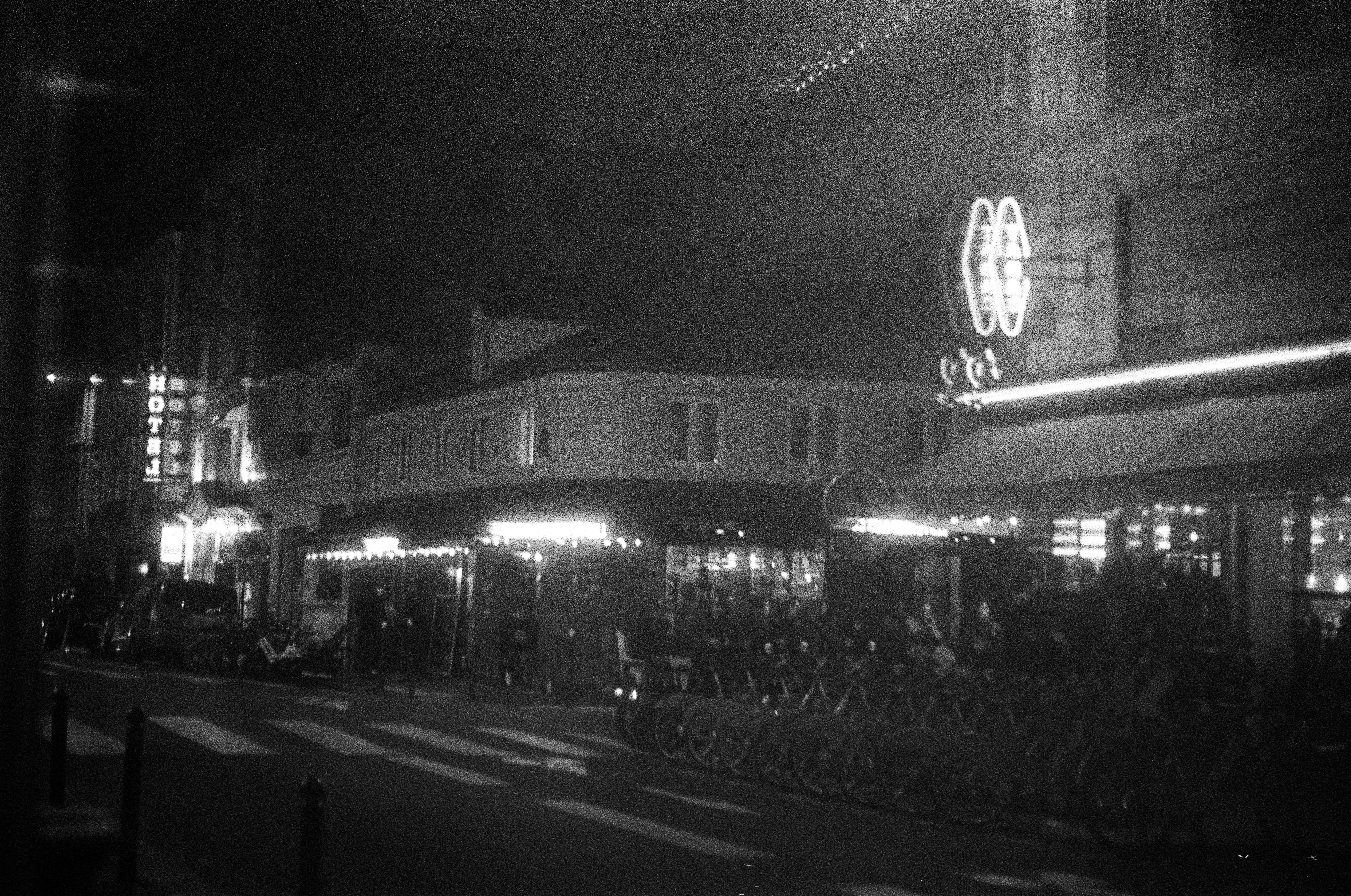 Pemandangan jalanan yang remang-remang di malam hari dengan tanda-tanda yang bersinar.