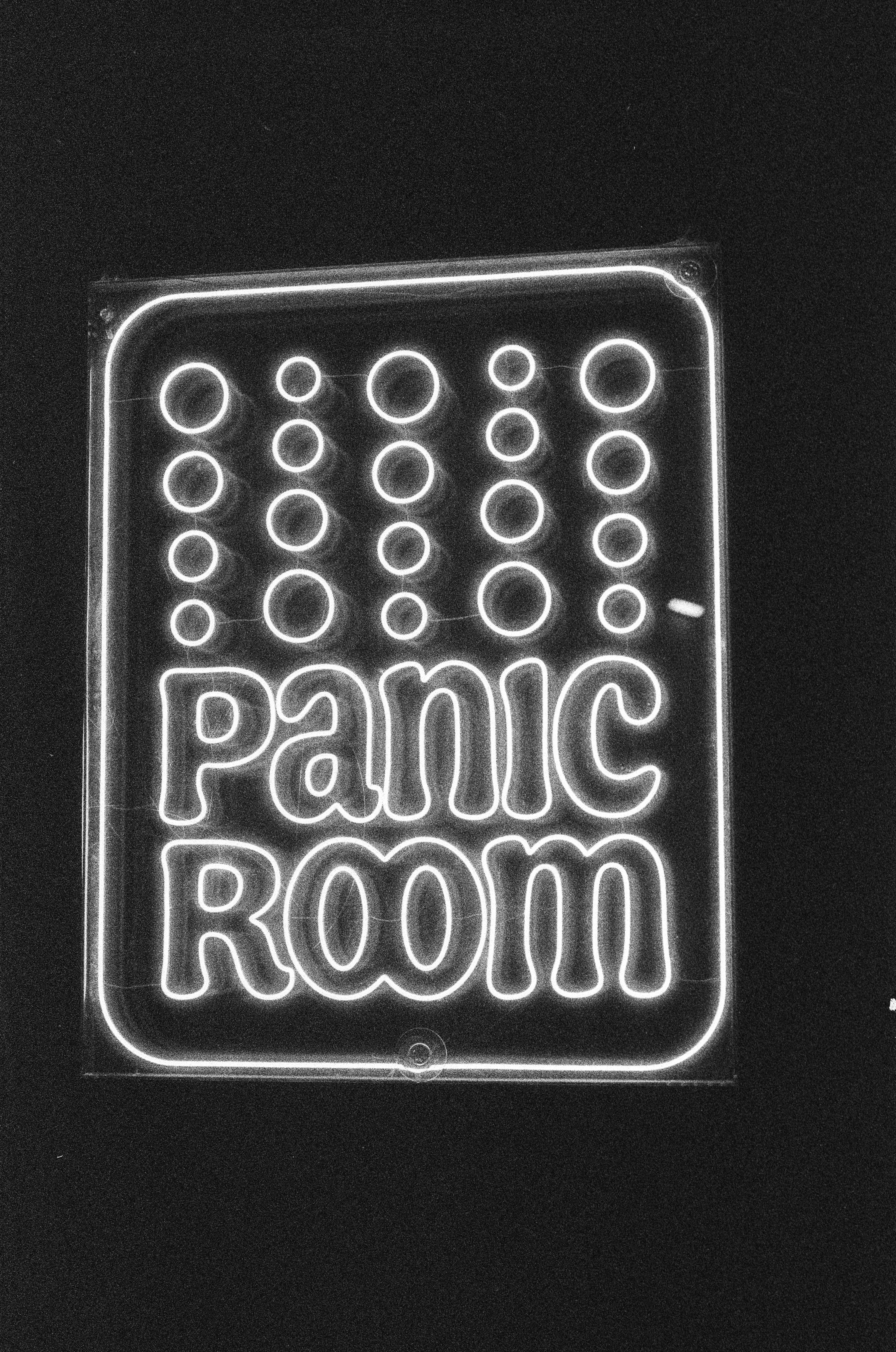 Tanda neon mengeja "ruang panik" dengan latar belakang hitam.