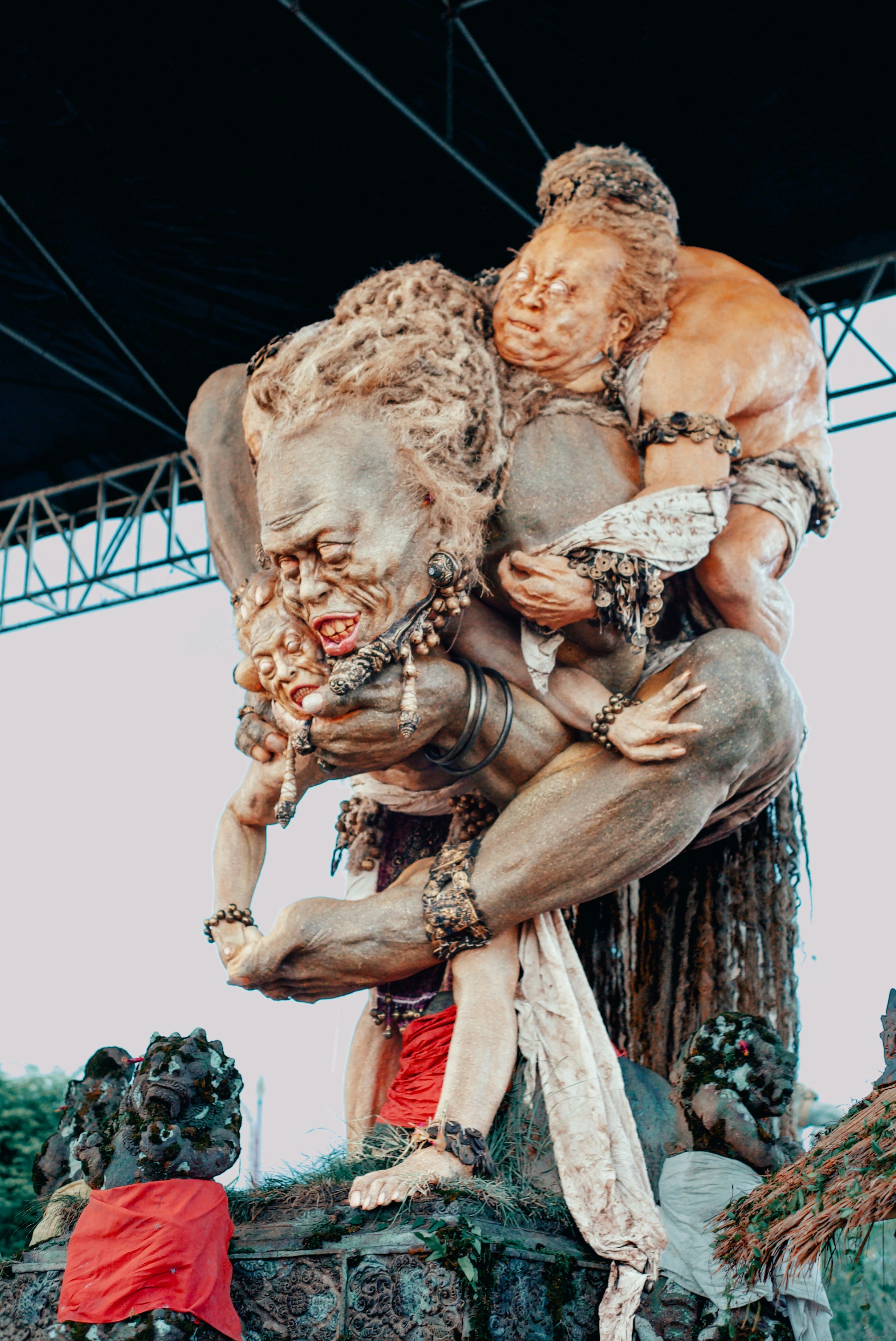 A large, grotesque sculpture of figures carrying a child.