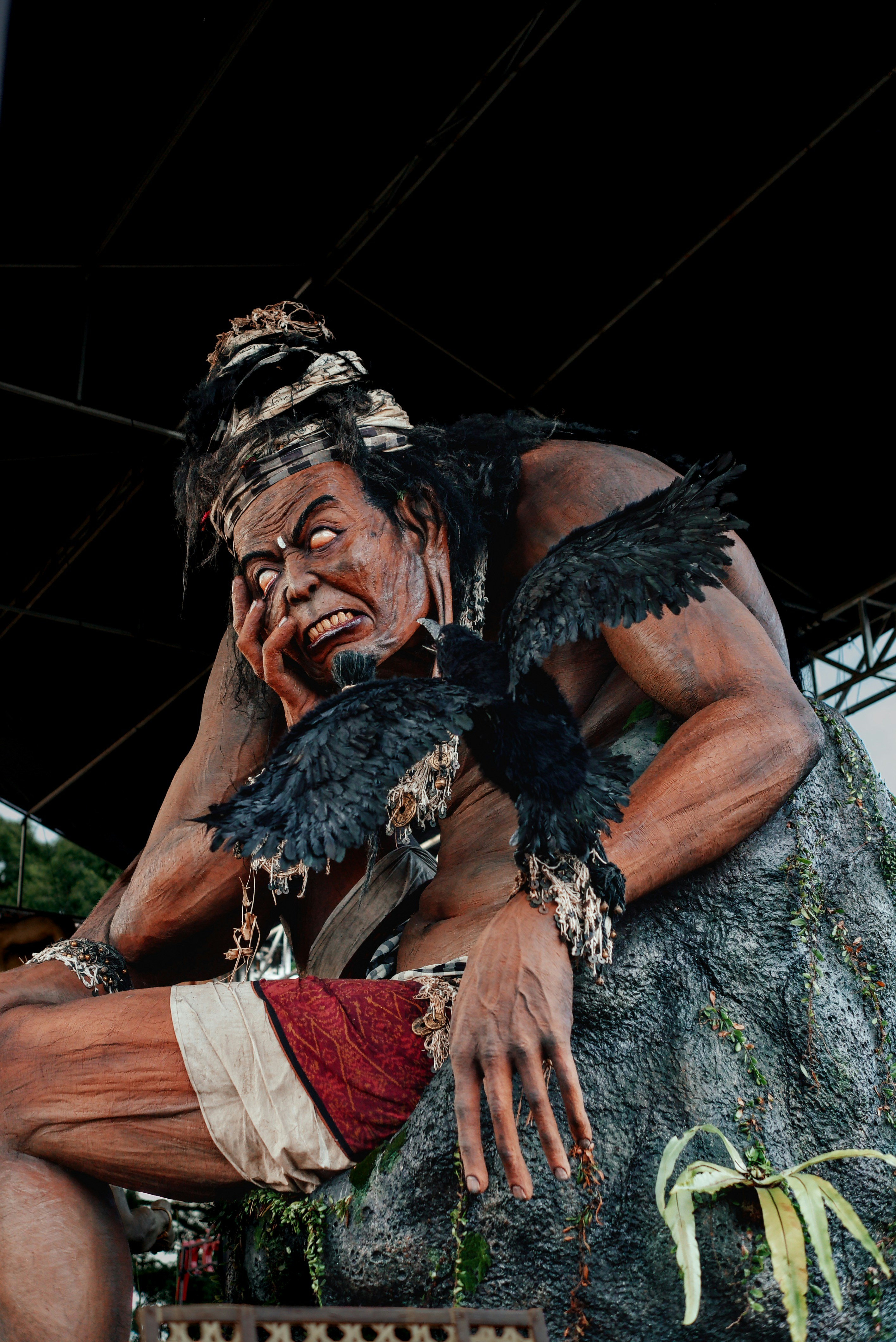 A giant statue of a man with dark feathers