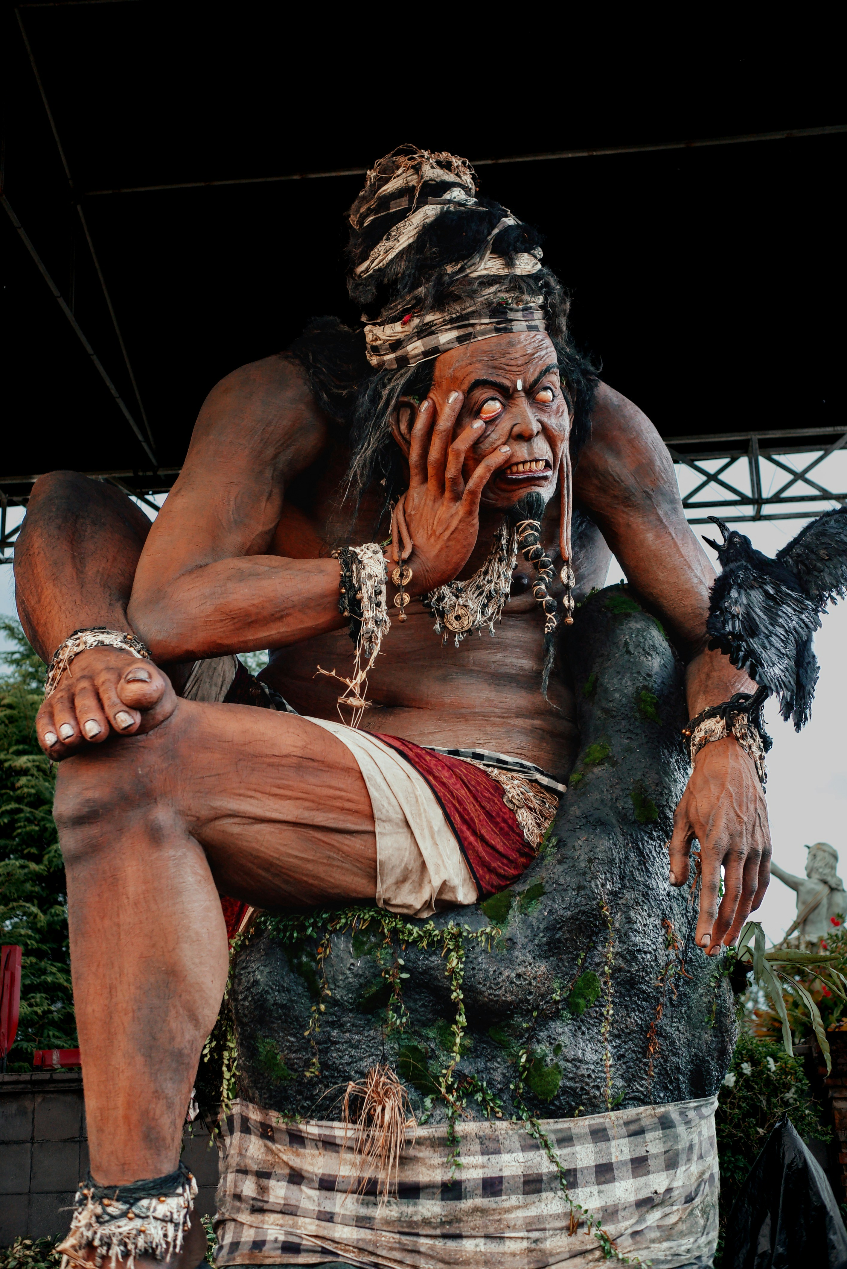Giant carved figure sits with hand on face