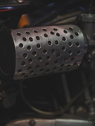 Close up of a motorcycle's perforated exhaust pipe.