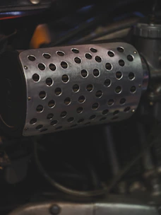 Close up of a motorcycle's perforated exhaust pipe.