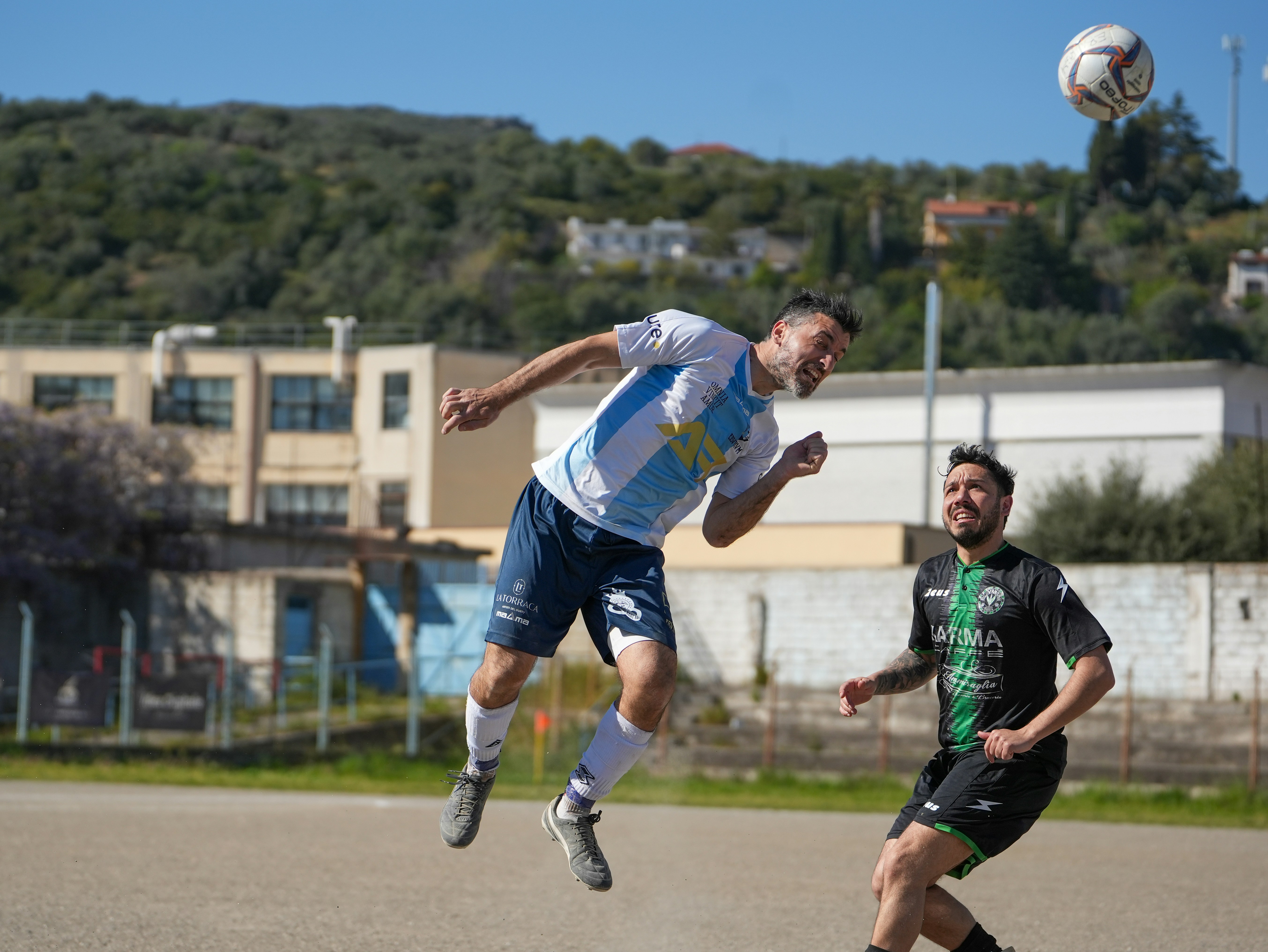 Two soccer players heading the ball during a game.