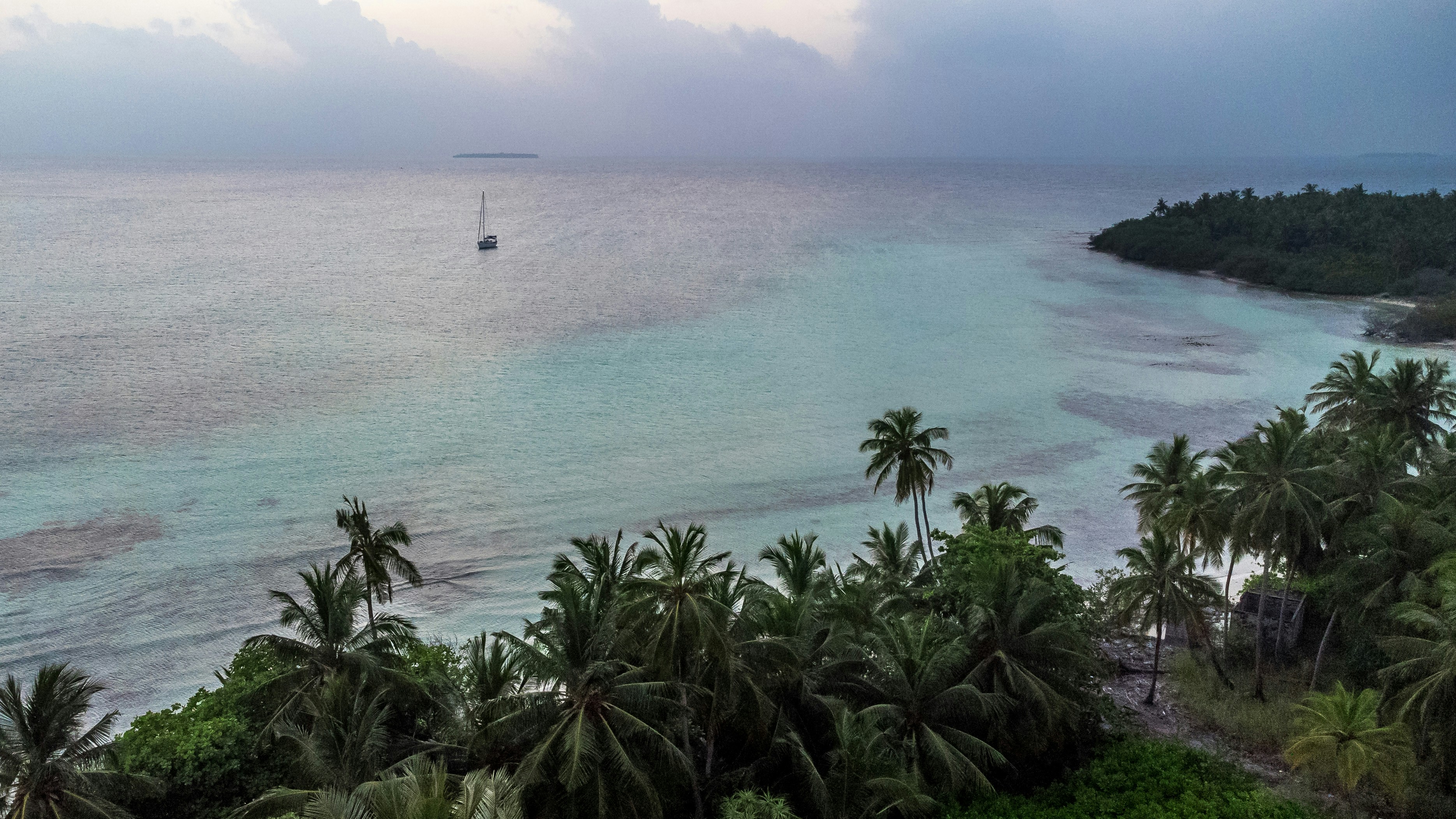 Sailboat on calm turquoise water near tropical island