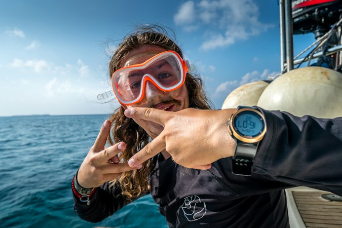 Scuba diver posing with a boat in the background