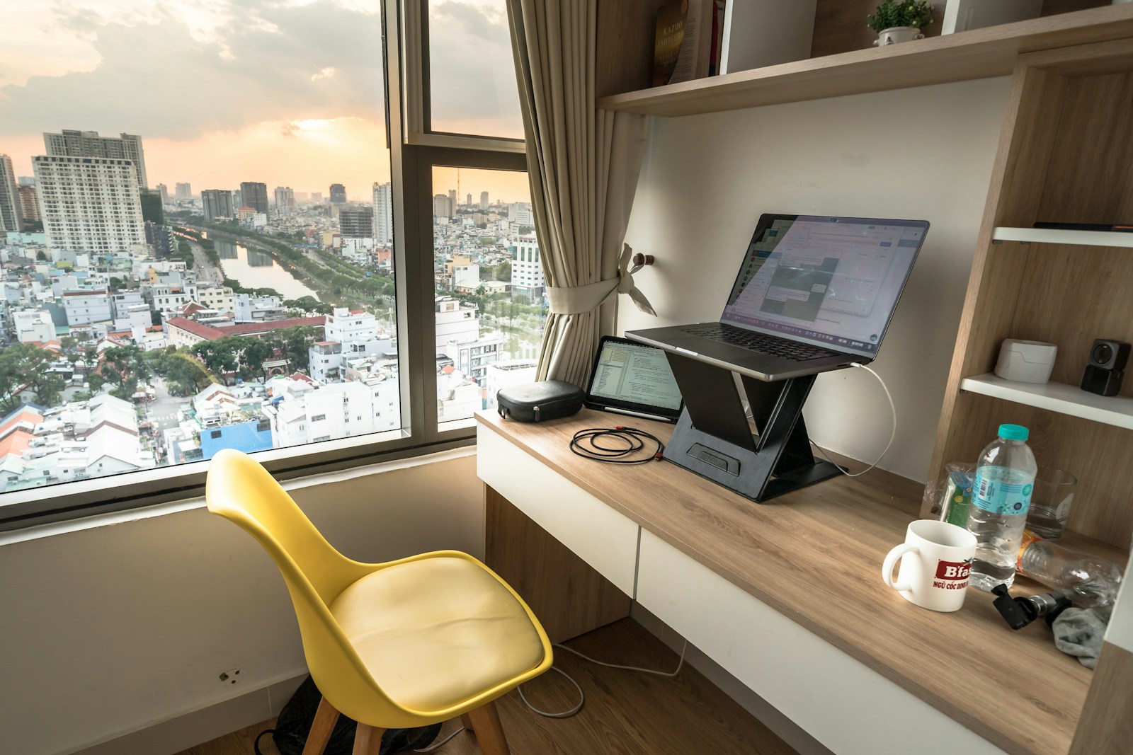 small apartment desk by window with laptop and city view