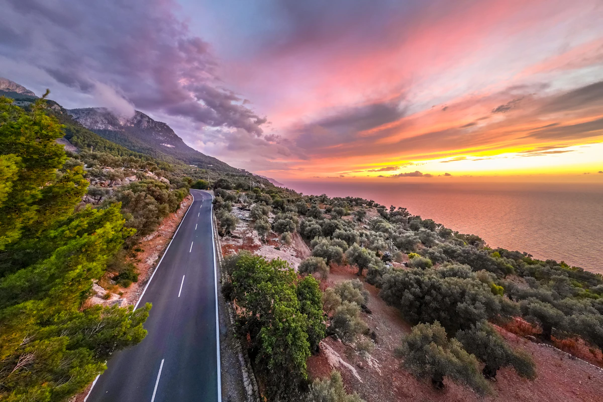Carretera costera con curvas bajo un cielo de atardecer